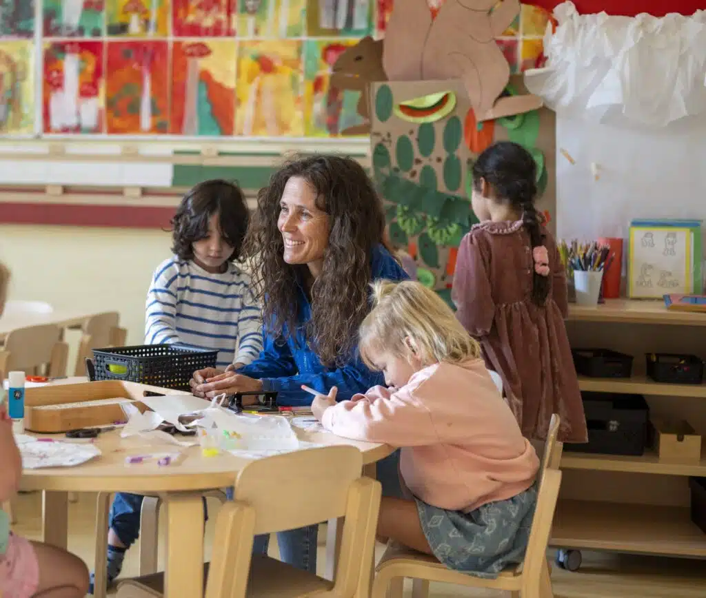 Teacher sitting at a table with children reading