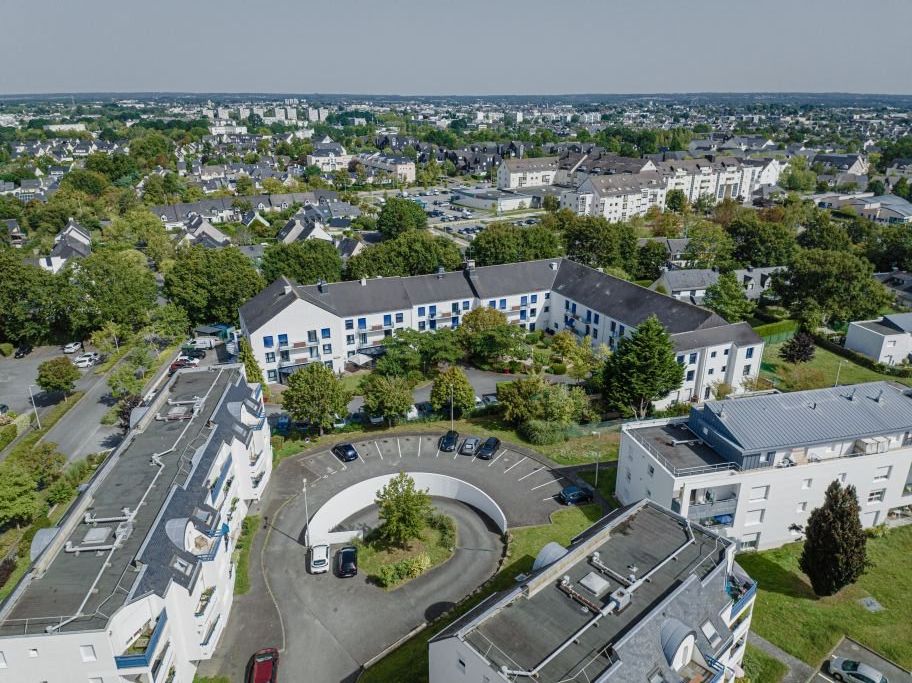 Aerial view of residence complex showing modern buildings	parking facilities	and surrounding urban landscape
