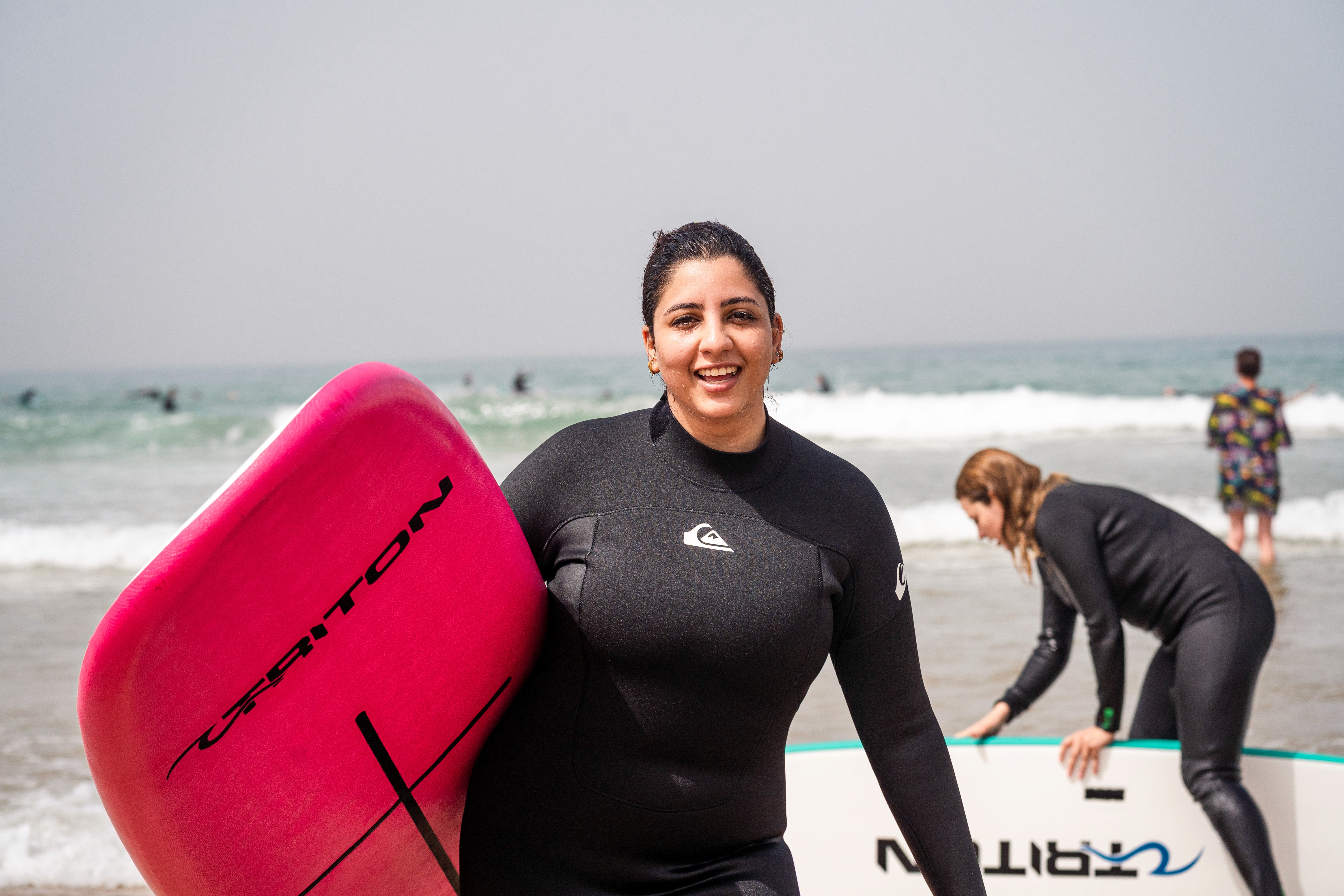 a group of people carrying surfboards on top of a beach
