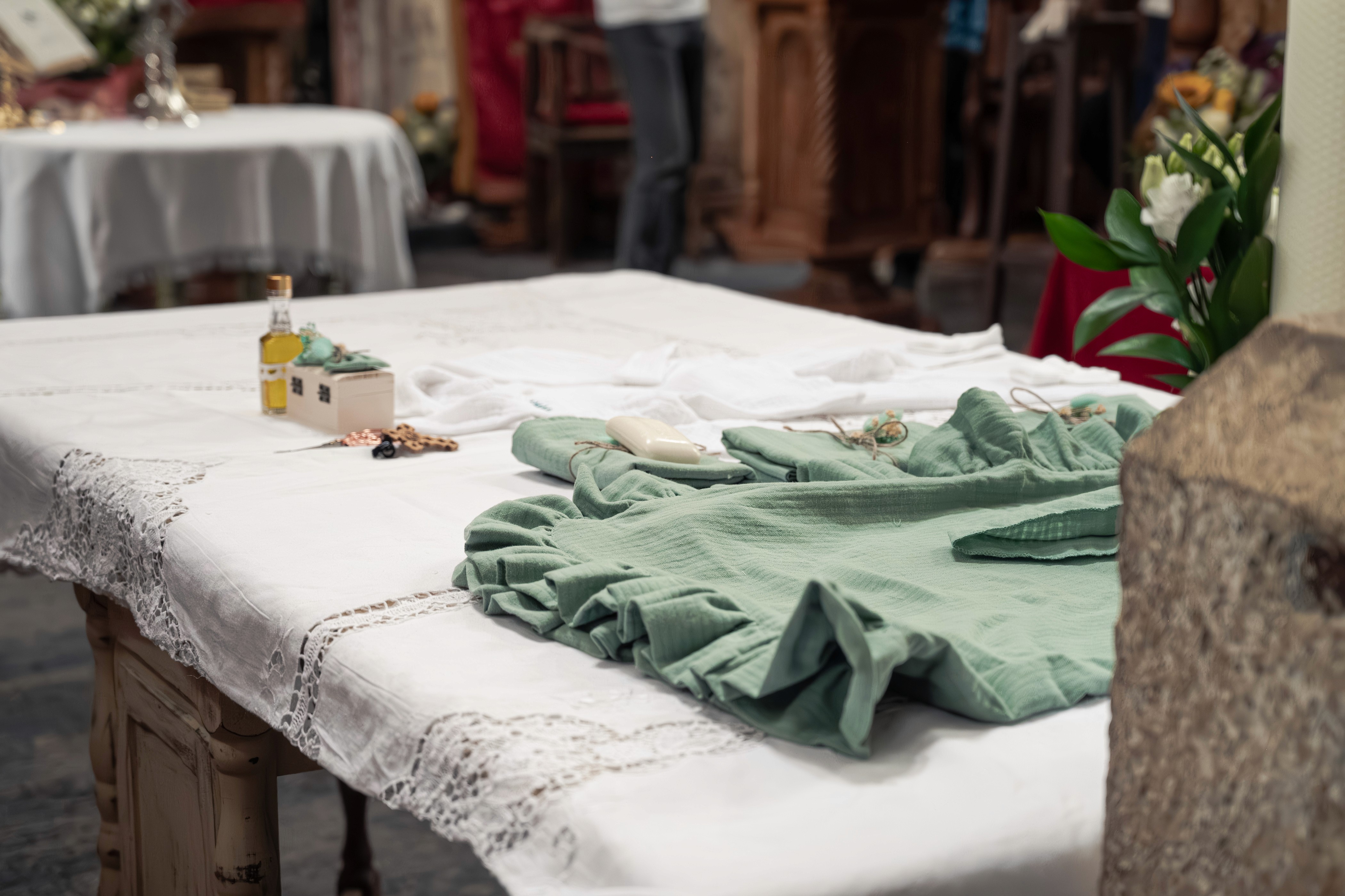 Masa pregătită pentru botez, cu trusou, lumânare și accesorii tradiționale — detaliu capturat într-o biserică din București.