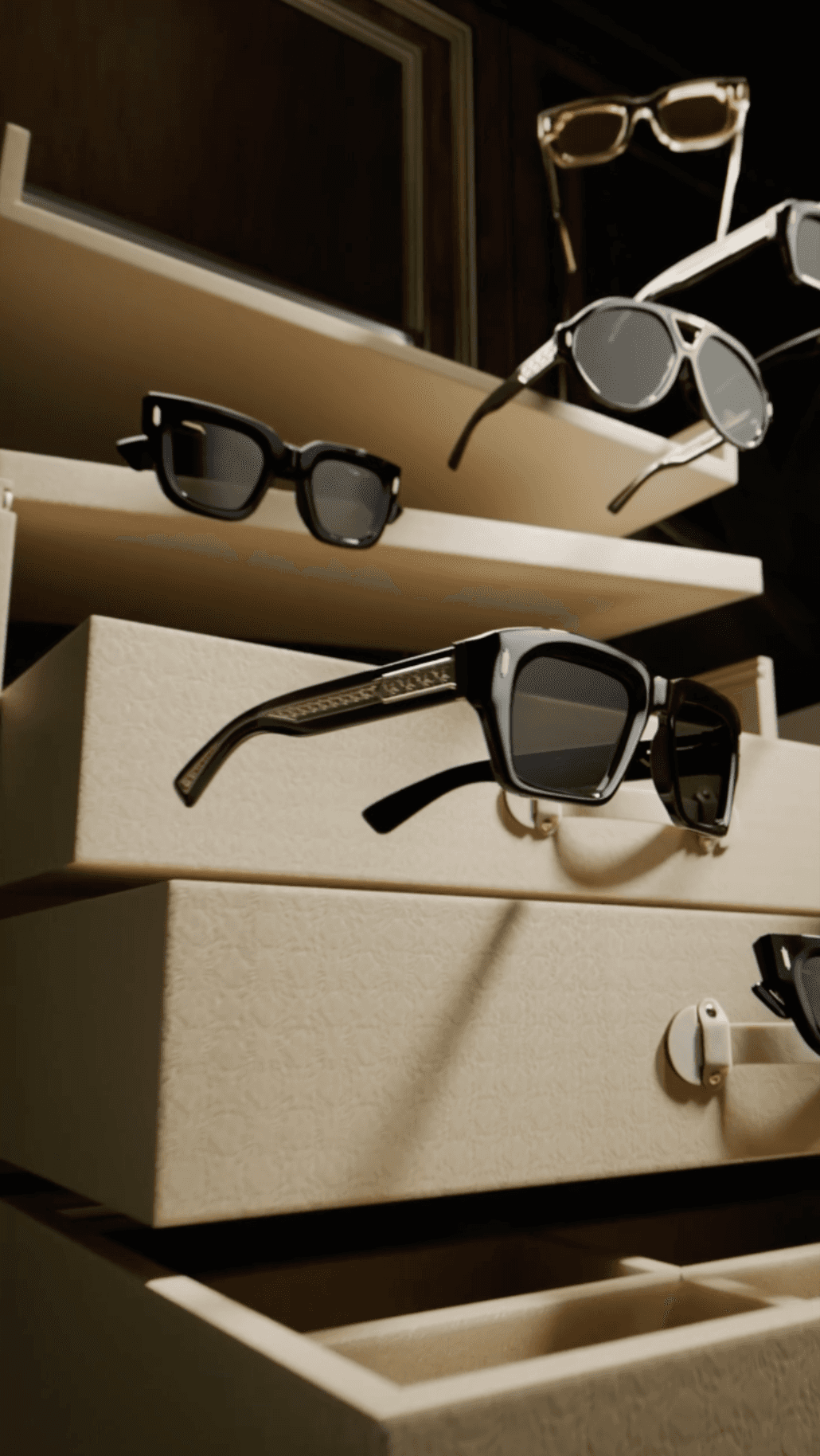 Thick-rimmed sunglasses are displayed on stacked, cream-colored 3D blocks in a sleek motion render