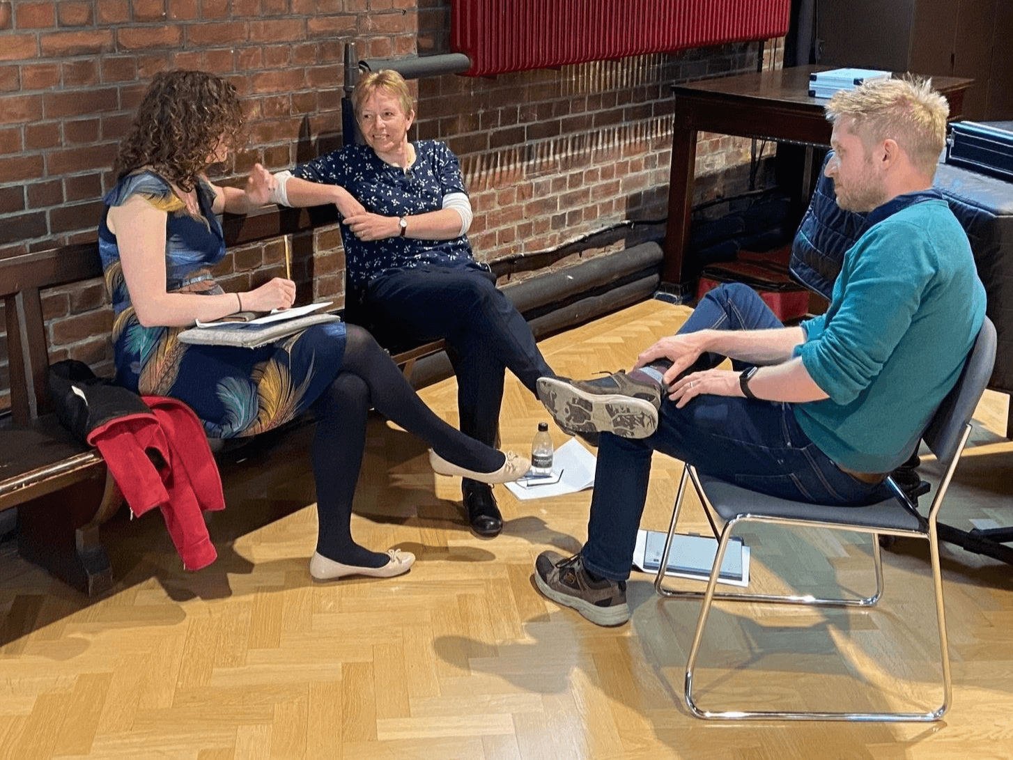 People sitting on chairs and standing in a workshop.