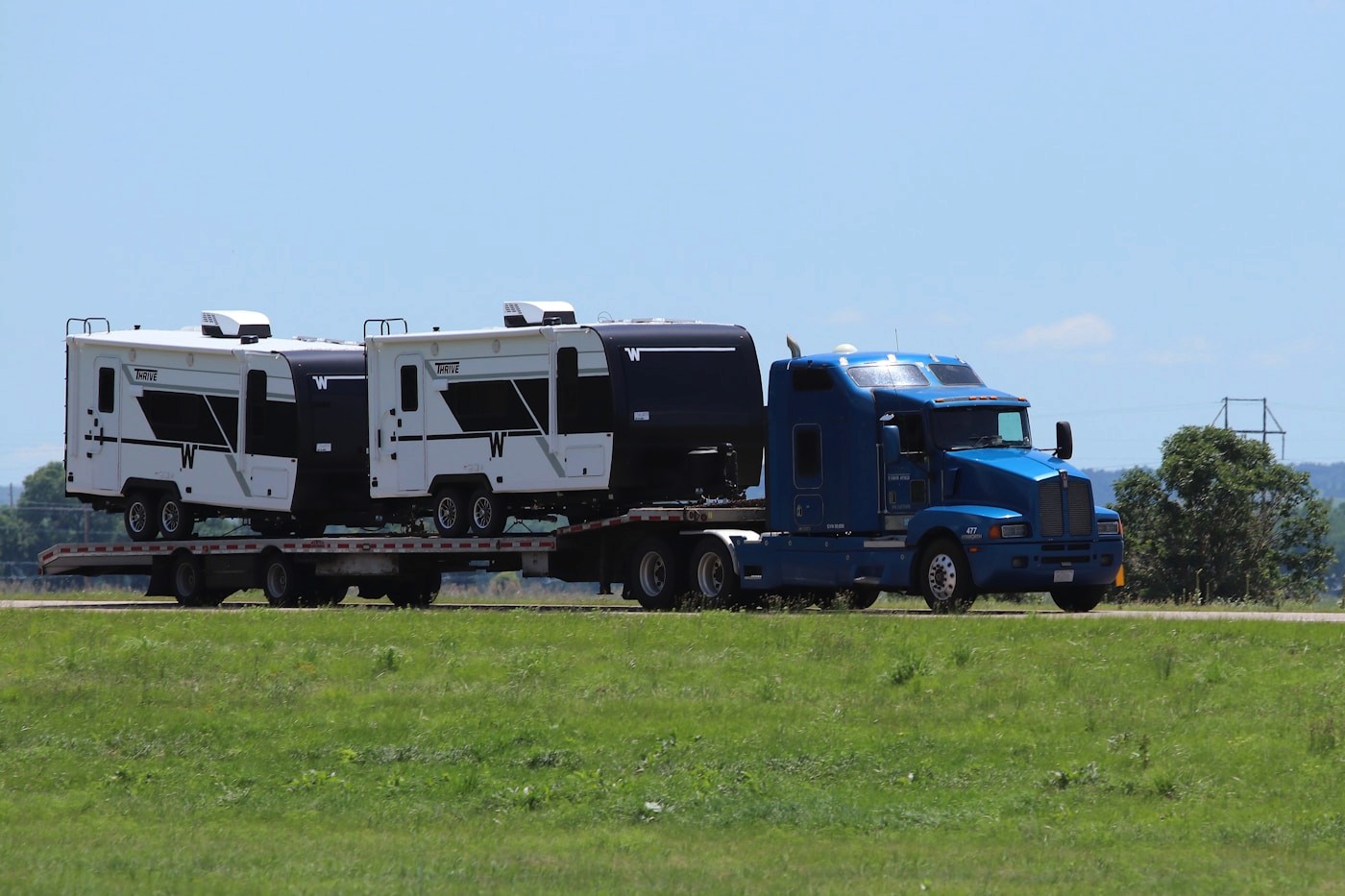 Blue semi truck hauling equipment on a flatbed