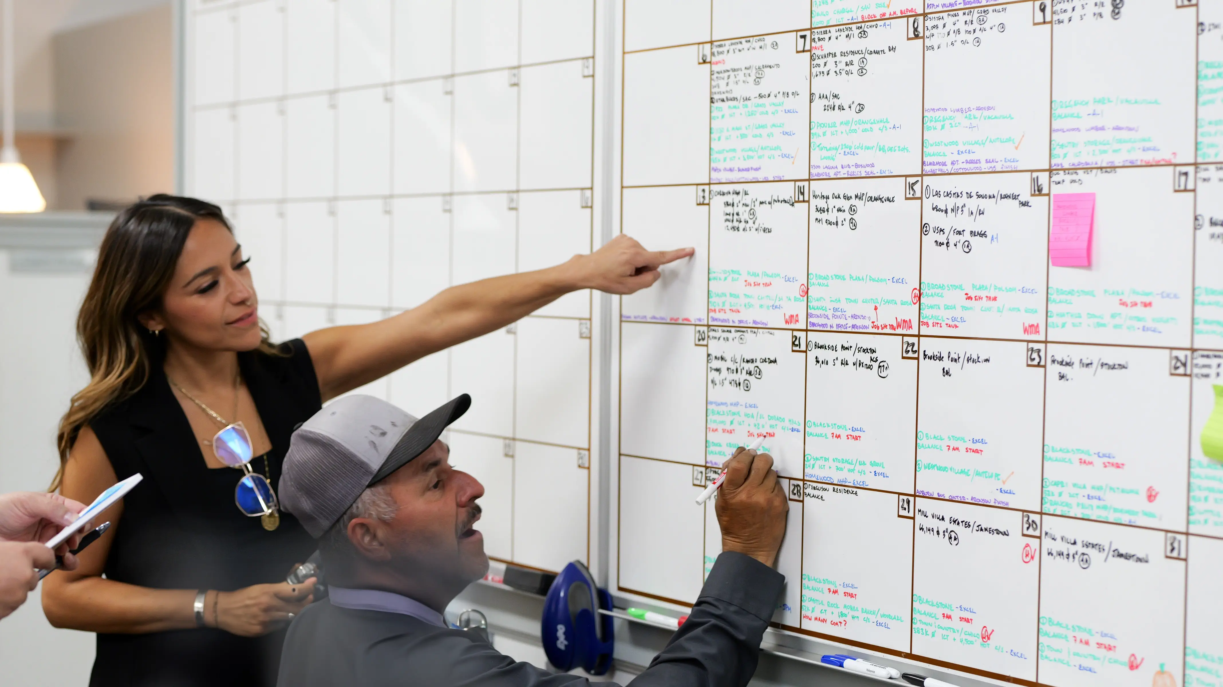 Two employees discussing project schedule at whiteboard