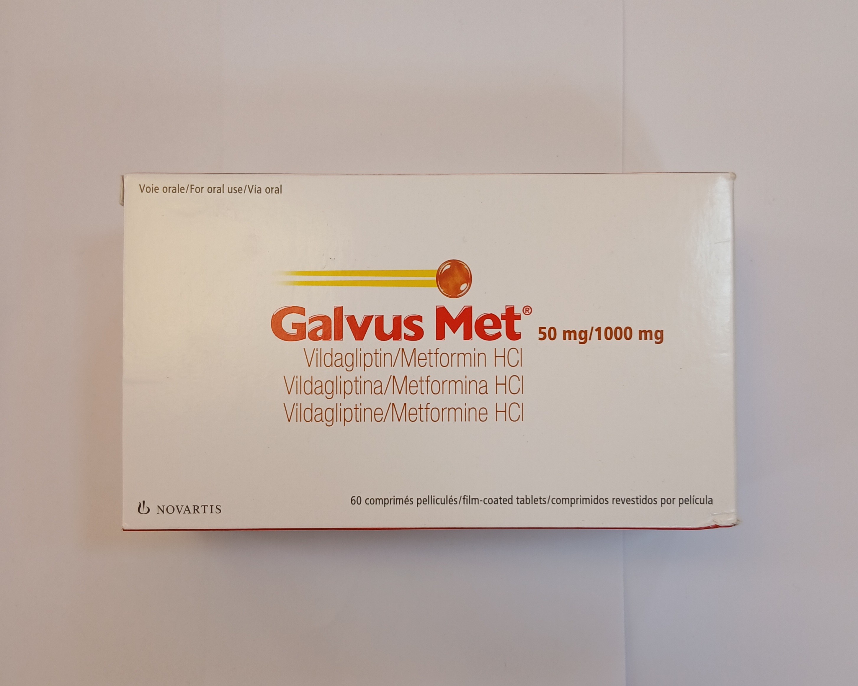 White cardboard box packaging containing 60 film-coated tablets arranged in a blister pack, with printed text in multiple languages and an orange and yellow logo near the top.