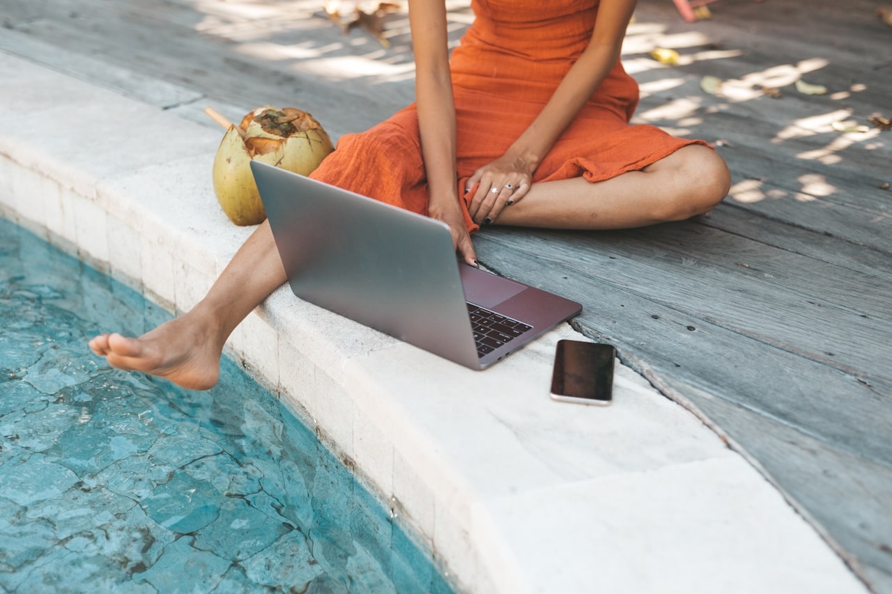 woman creating a wishlist on laptop beside pool