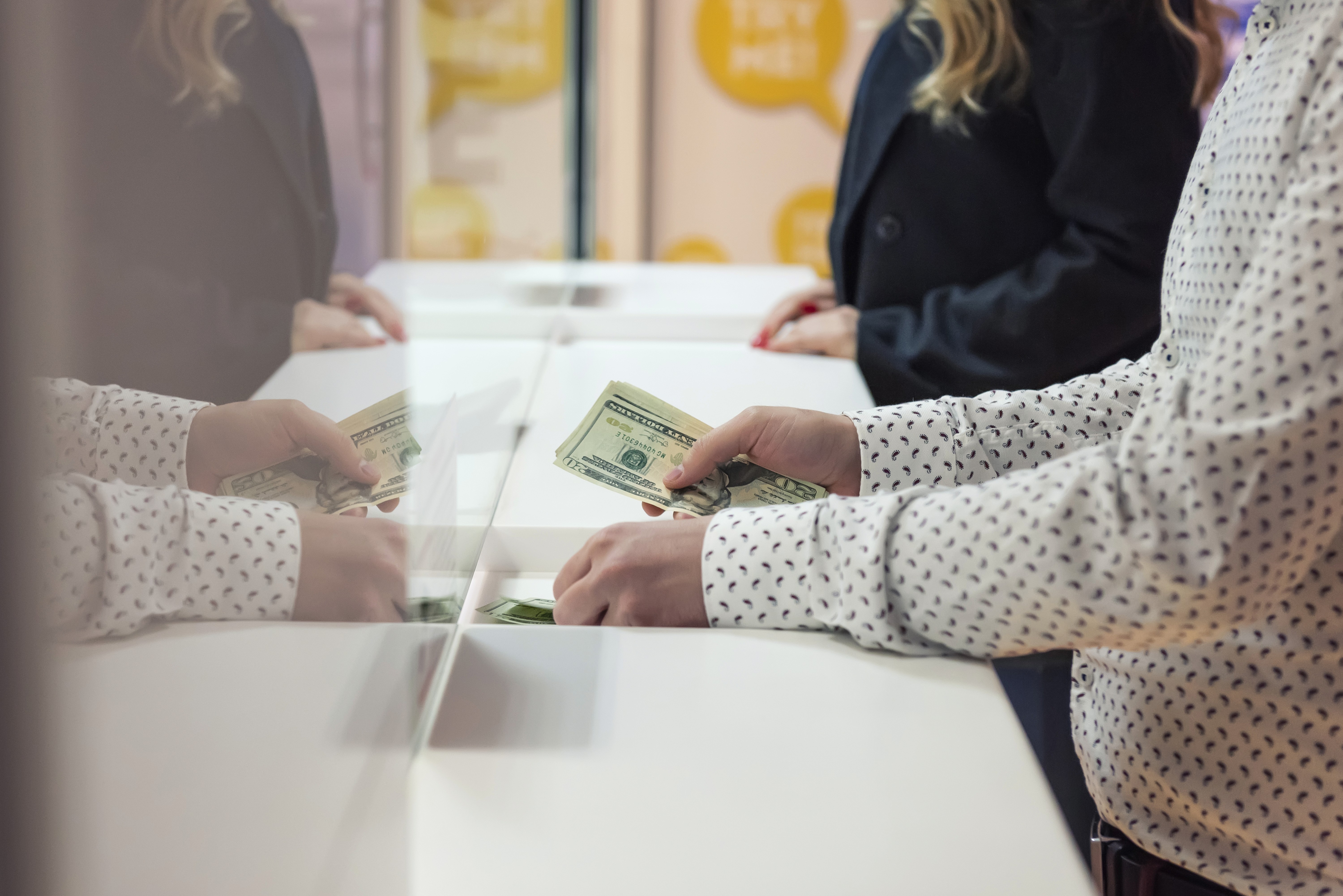 A person passing money to a bank teller