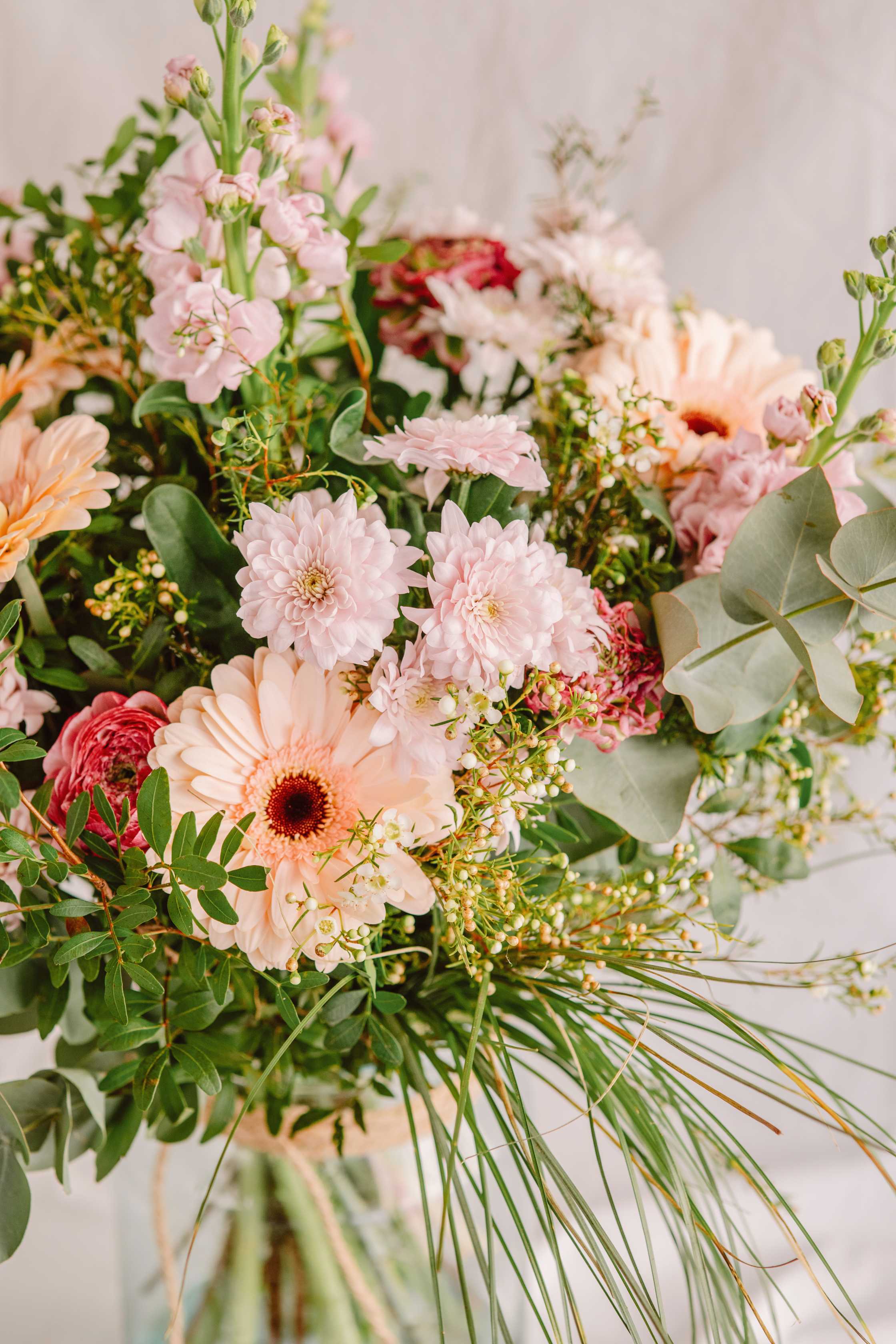 Detall d’un ram amb gerbera préssec, crisantem rosa clar, ranuncle i eucaliptus. Combinació de flors silvestres amb textures naturals i tonalitats tendres.