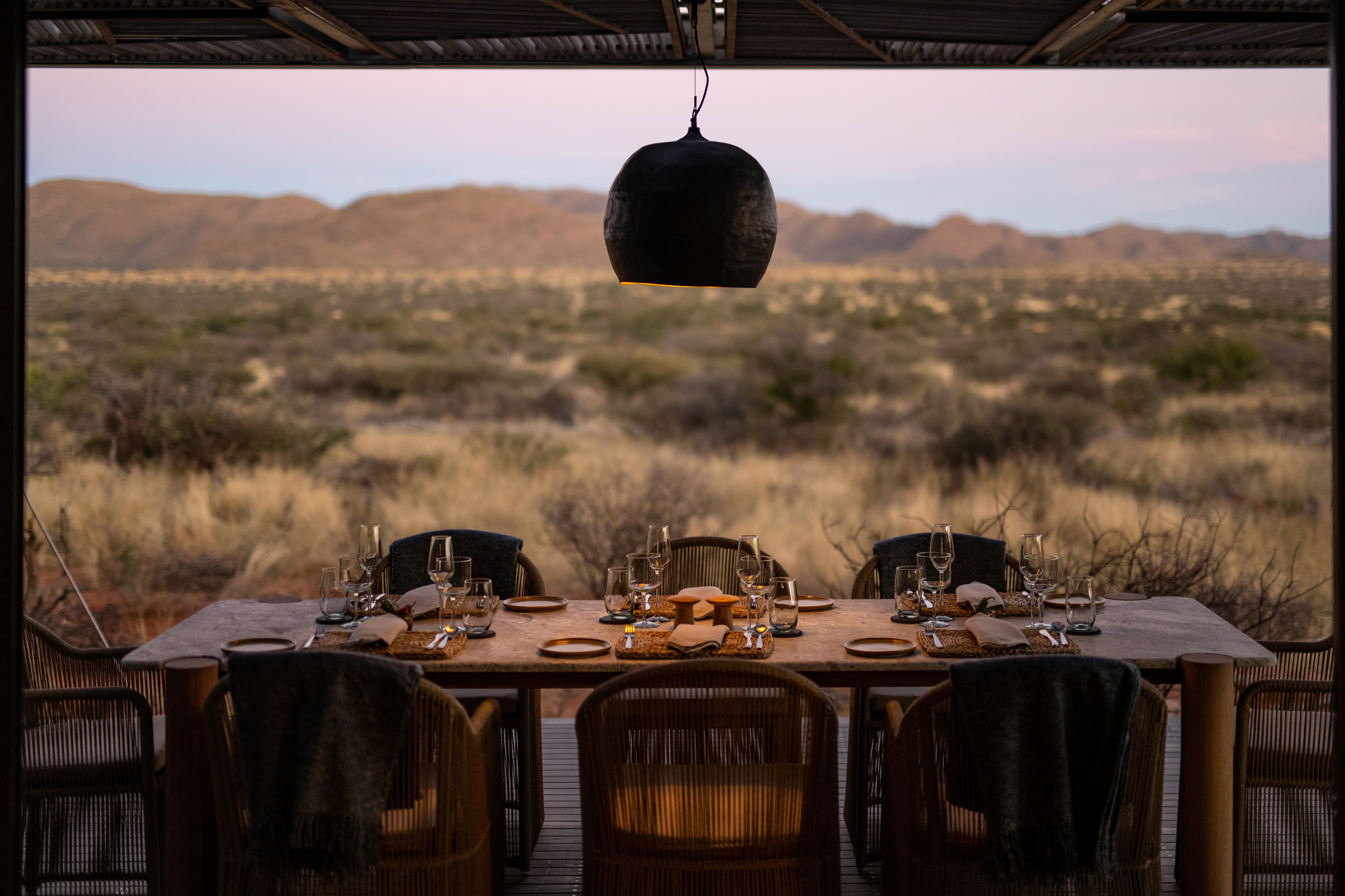 A private dinner table set on an open deck overlooking the Kalahari, South Africa