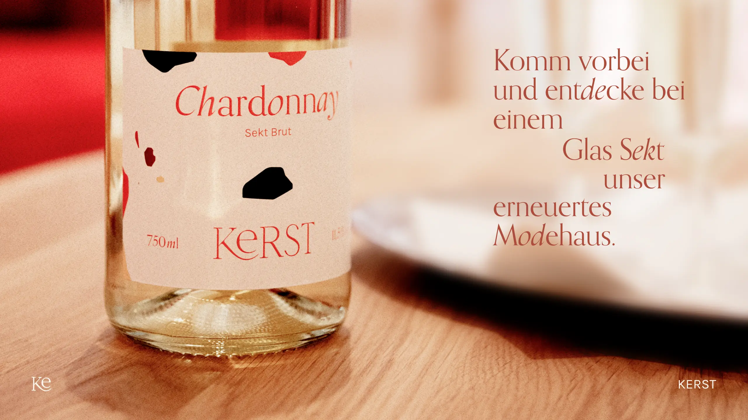 Lifestyle-Foto einer gebrandeten Sektflasche mit individuellem Etikett für Kerst Hochzeitsmode, begleitet von einer Einladung, das neu gestaltete Modehaus in Ludwigsburg bei einem Glas Sekt zu besuchen.