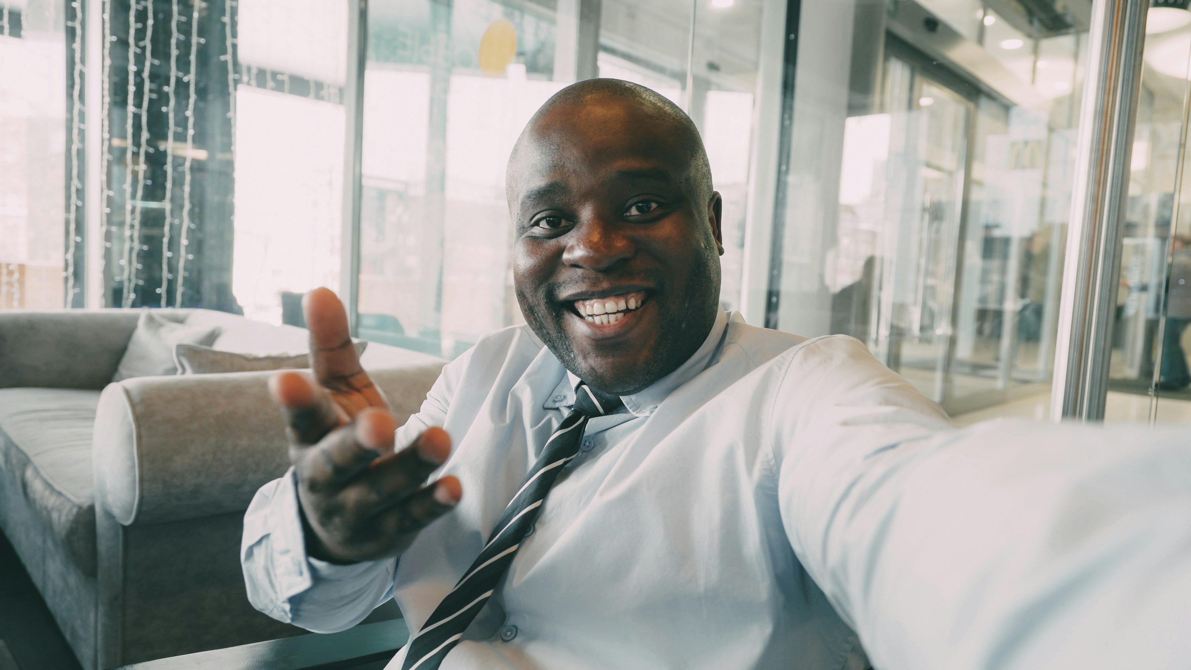 Smiling businessman waves at the camera in office.