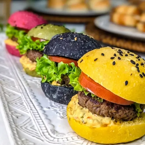 Mini hamburguesas gourmet con salsa especial en pan de colores para catering de cumpleaños en Santiago.