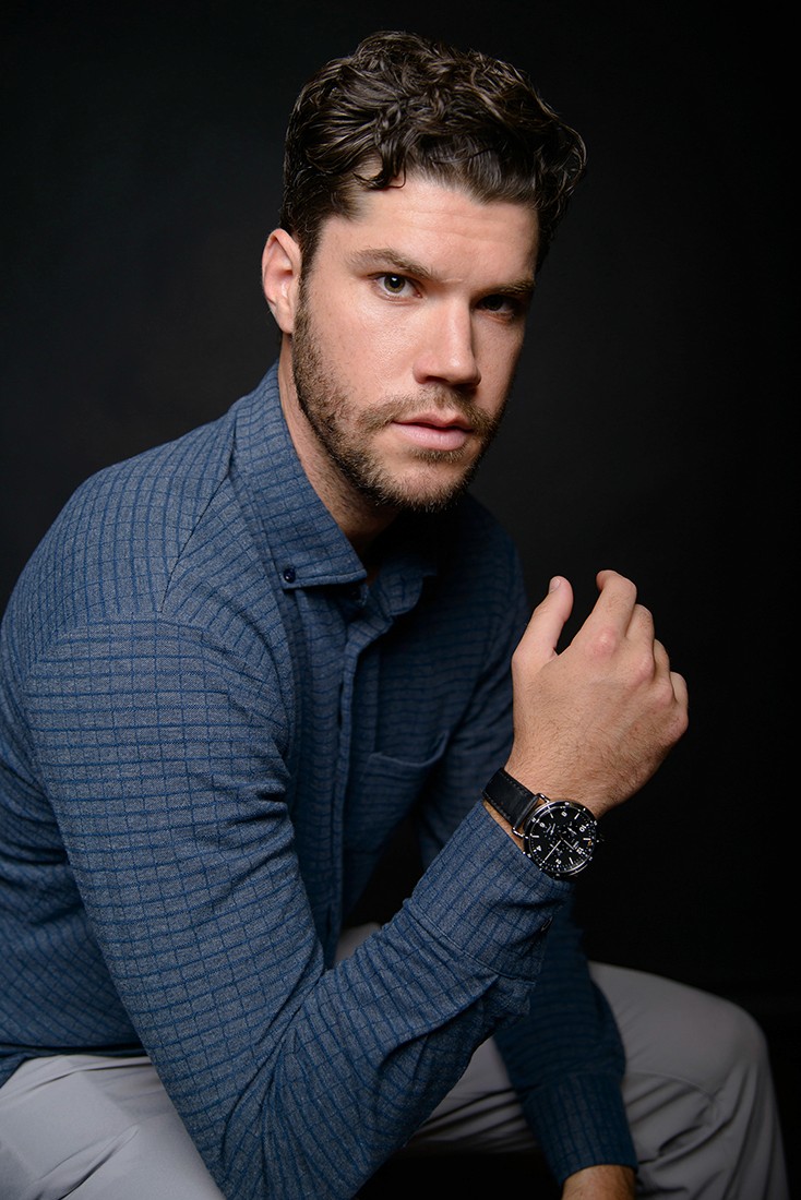 Male actor headshots he is wearing blue and photographed against a dark gray backdrop