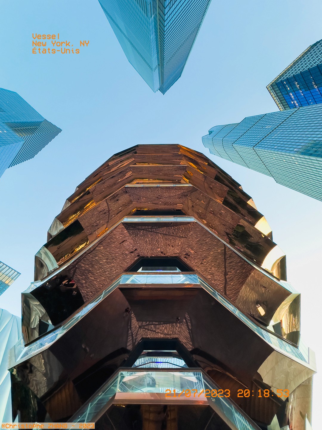 Perspective unique du Vessel et des tours environnantes sous un ciel bleu à New York.