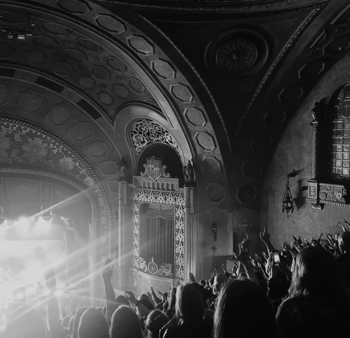 A crowd in a theatre venue, dancing to the music concert.