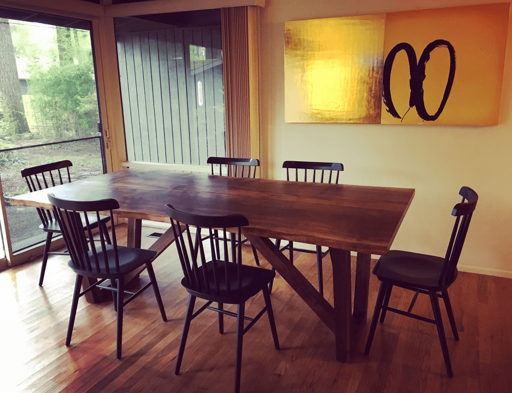 A large dark wood dining table is surrounded by black wooden dining chairs.