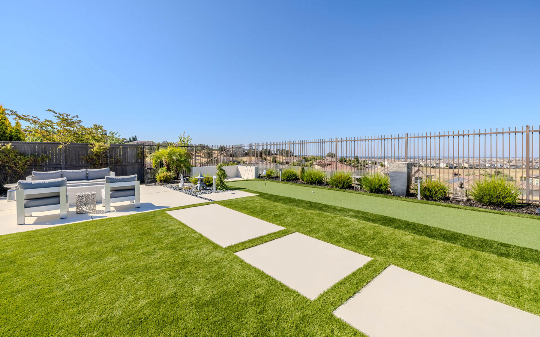 A vibrant backyard with green artificial grass and a stylish patio, ideal for enjoying sunny days and outdoor activities.