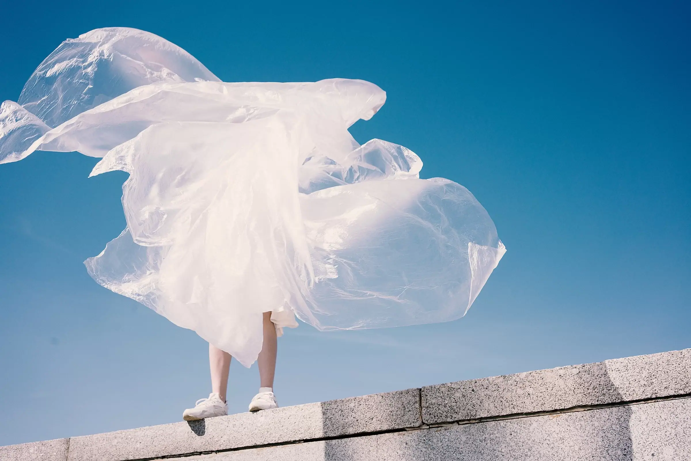 Person mit wehender weißer Tuchfahne vor Berggipfel und blauem Himmel – Symbol für Nachhaltigkeitsziele und EcoVadis-Rating