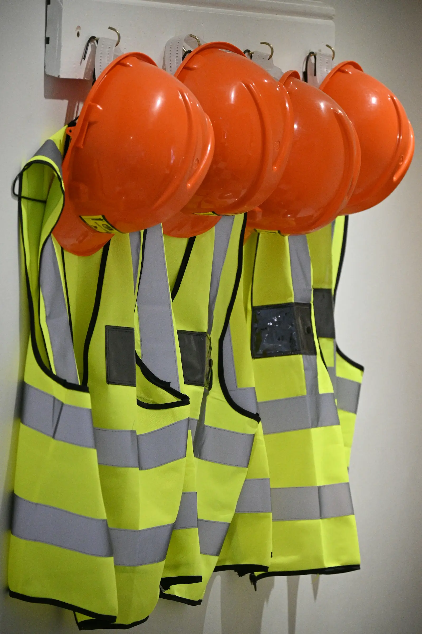 High-visibility safety vests and hard hats hanging in a workplace