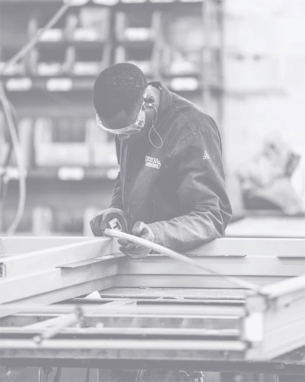 Ein Arbeiter misst sorgfältig einen Holzrahmen im Werk und zeigt handwerkliche Präzision.