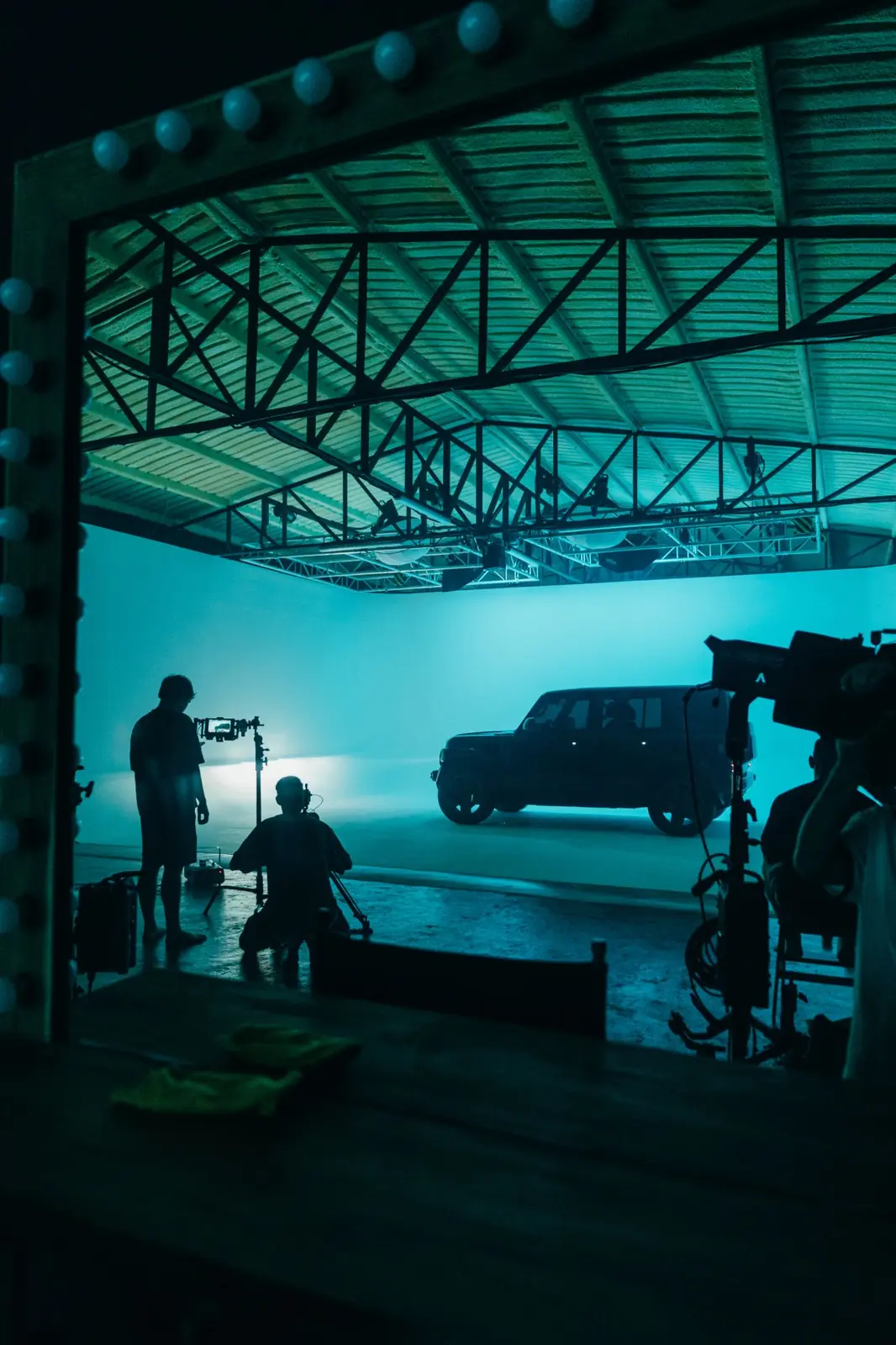 The teal-lit set and the Chery V23 seen through the make-up mirror in Studio 150