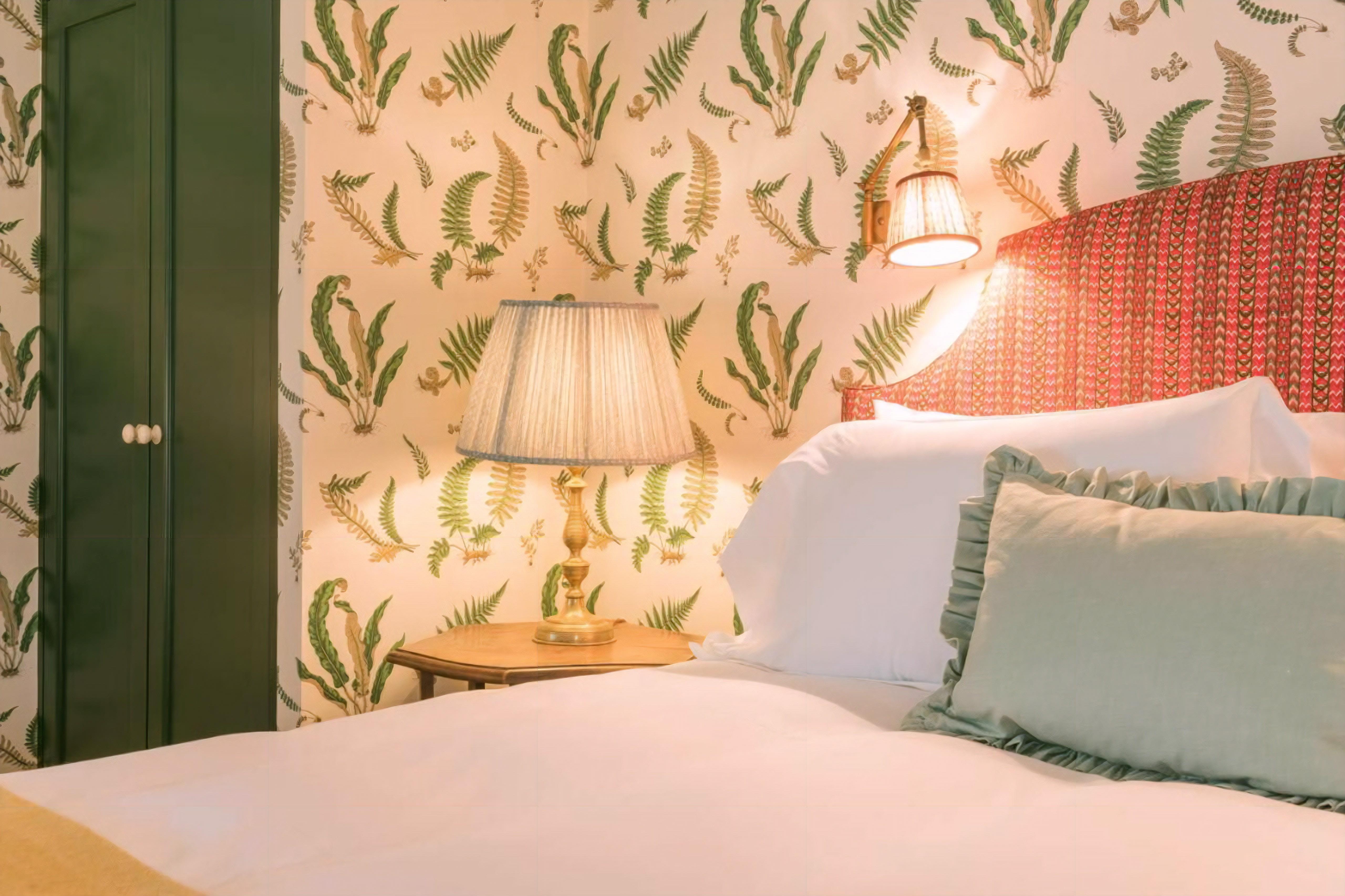 The Bear Inn boutique bedroom with patterned wallpaper, upholstered headboard and hospitality refurbishment finishes