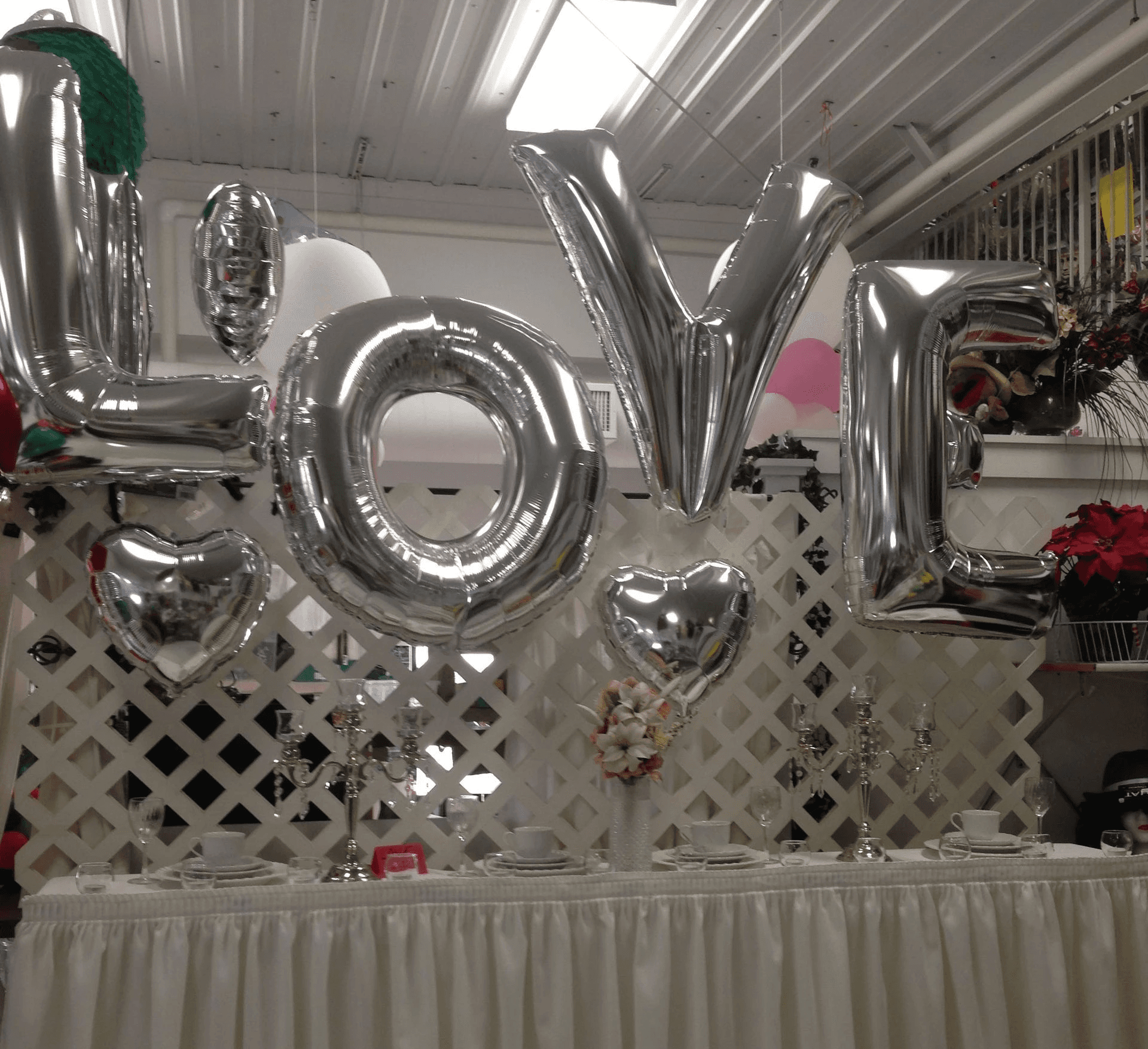 Silver balloon letters spelling LOVE displayed above a white balloon backdrop designed by Be Bold Balloons