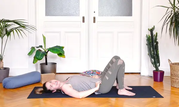 Woman lying on a yoga mat doing gentle breathwork – postnatal yoga class for pelvic floor activation and slow healing in the first 40 days after birth