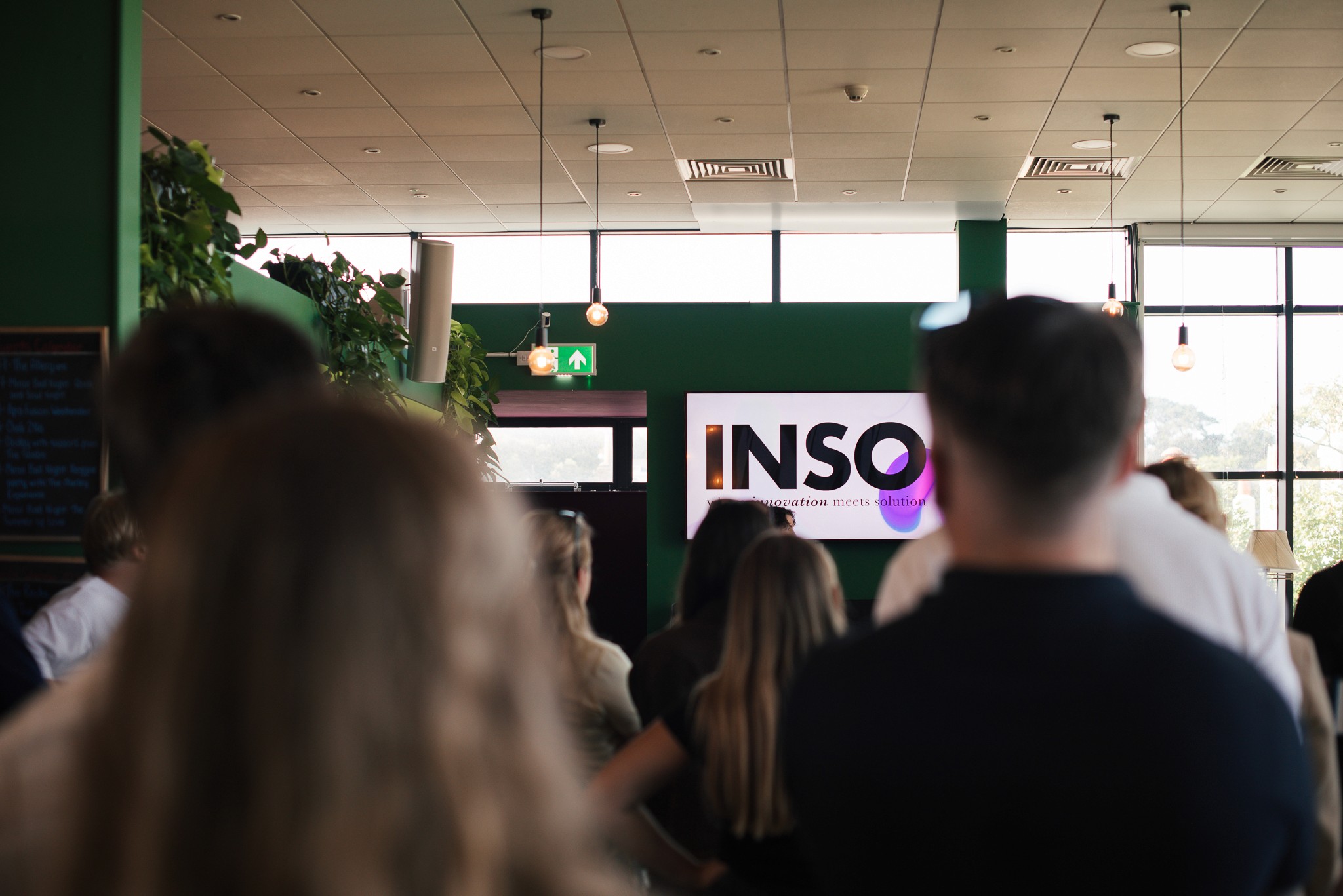 Four diverse professionals collaboratively working on a laptop, with one person pointing at the screen while others observe.