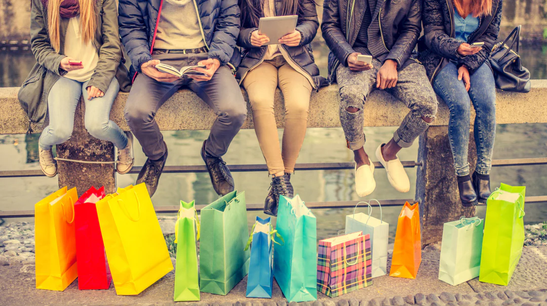 people sitting on ledge with shopping bags on the ground