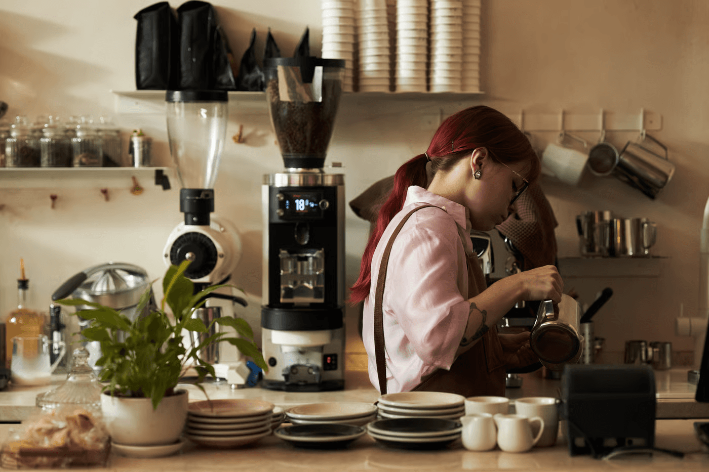 Frau mit roten Haaren, die in einem cafe arbeitet und Kaffee eingießt