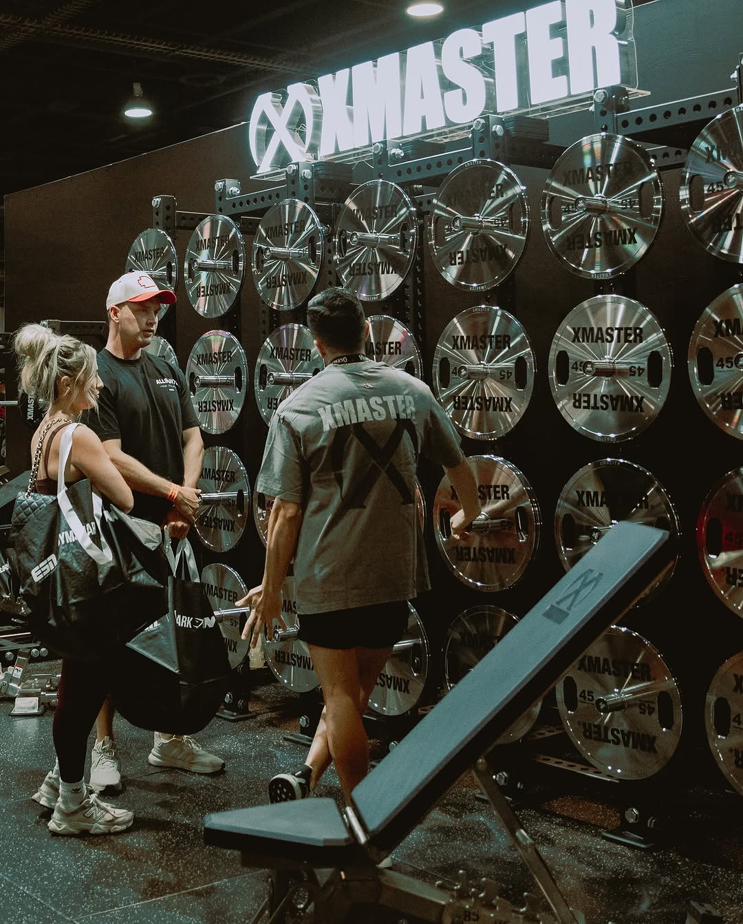 Two individuals are working out in a gym, focusing on dumbbells and strength training equipment.