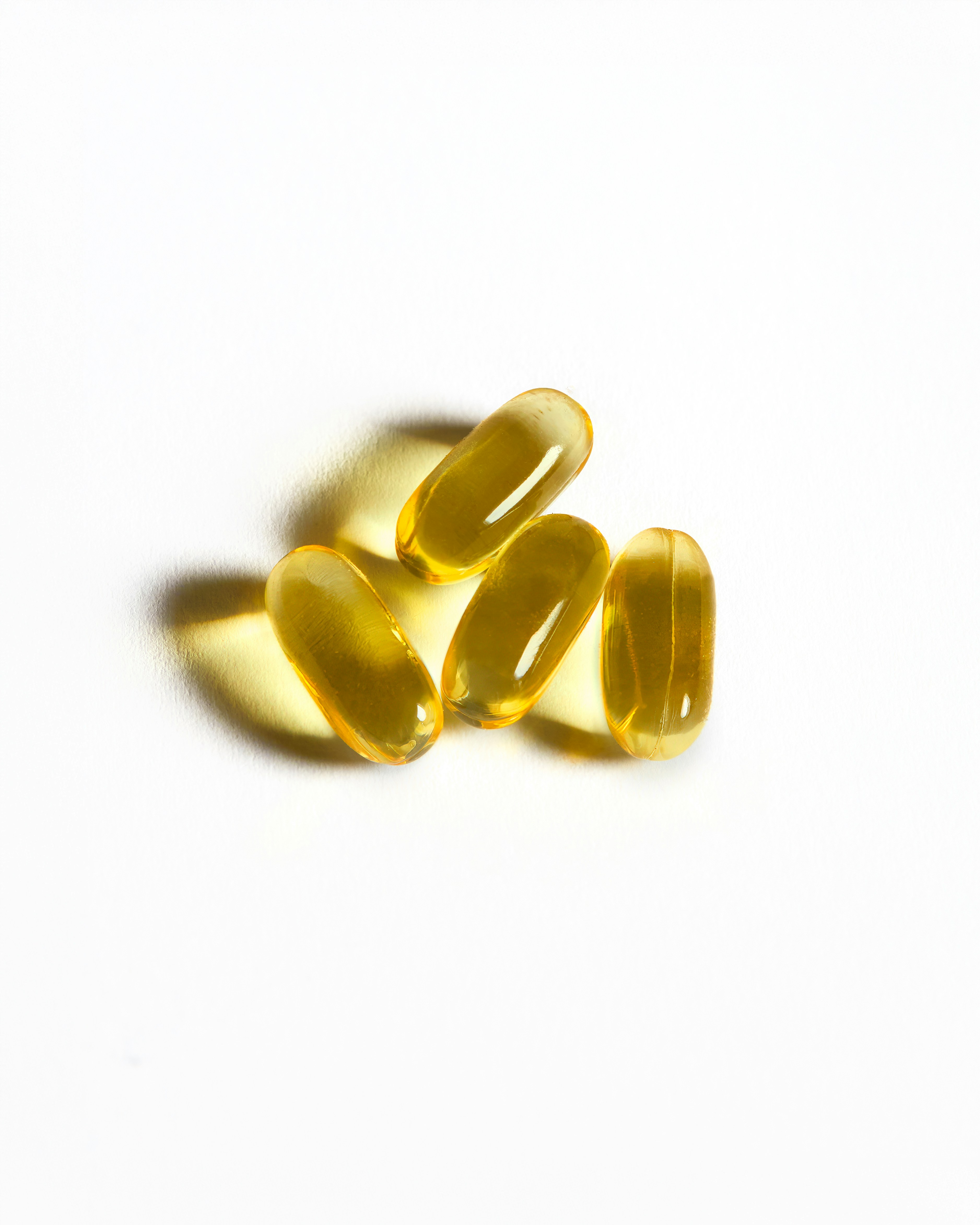Four yellow capsules sit on a white surface.