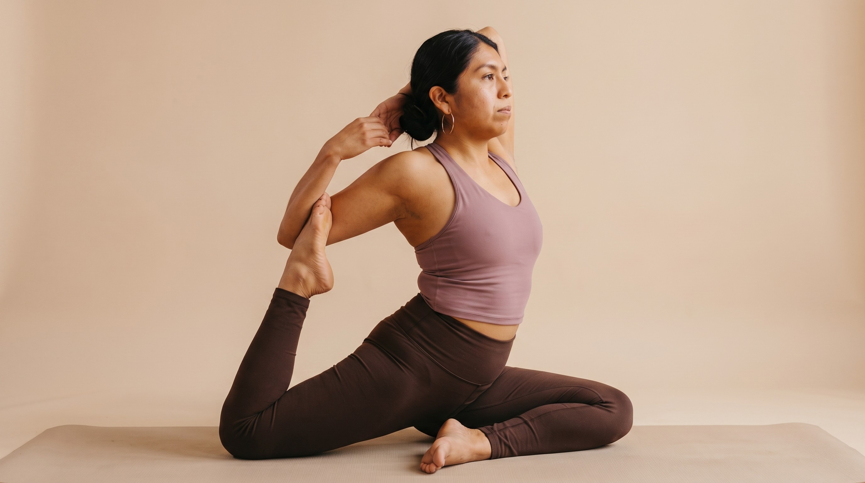 Student in a deep pigeon stretch reaching back to hold her raised foot during a Power Vinyasa class