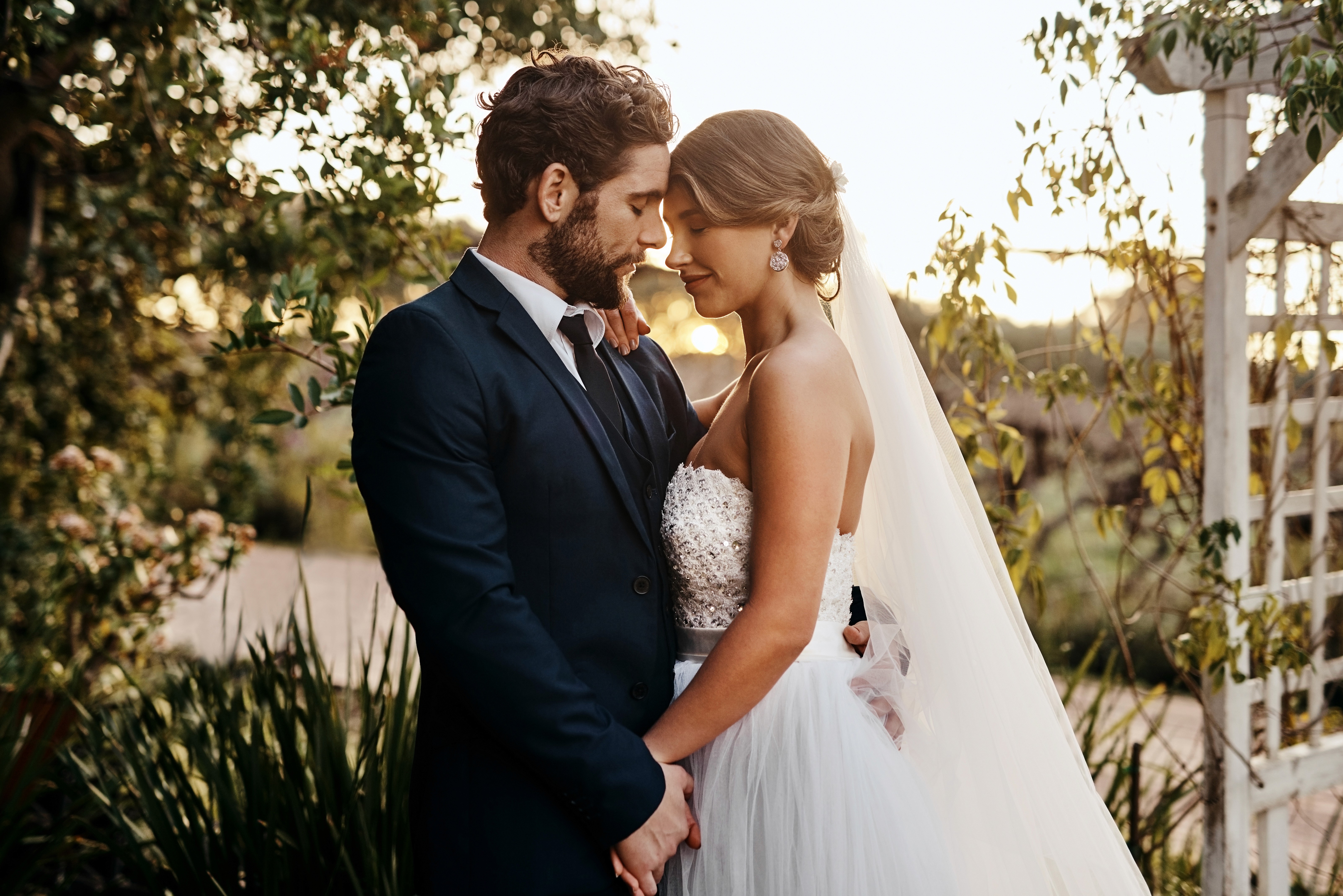 Bride and groom sharing an intimate moment in a garden at golden hour