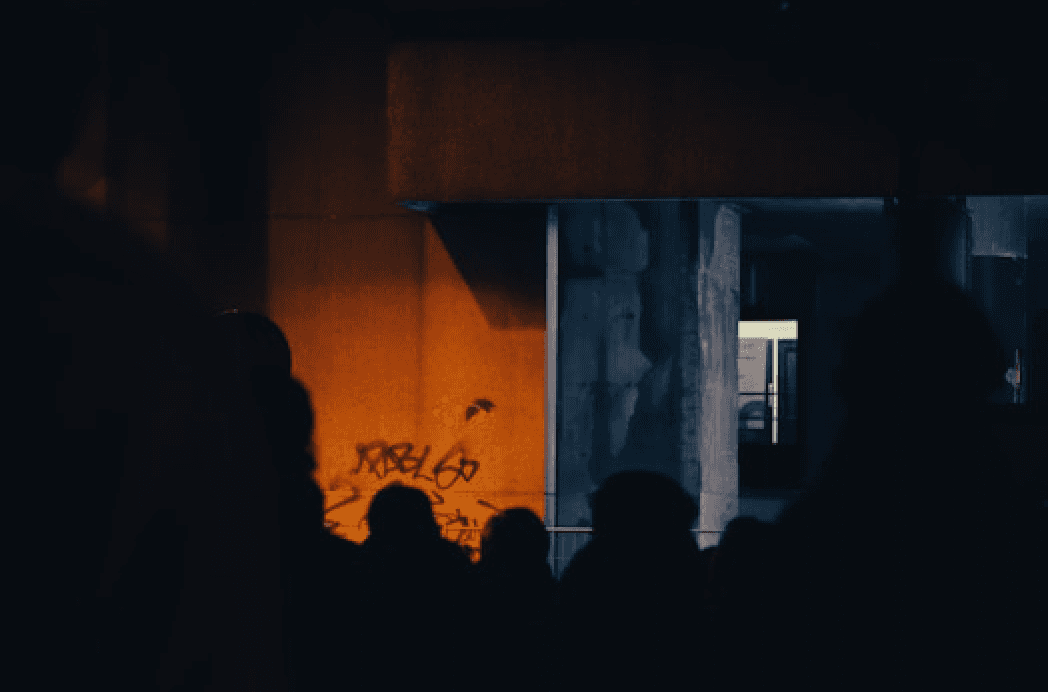 Silhouettes under a bridge lit by warm light