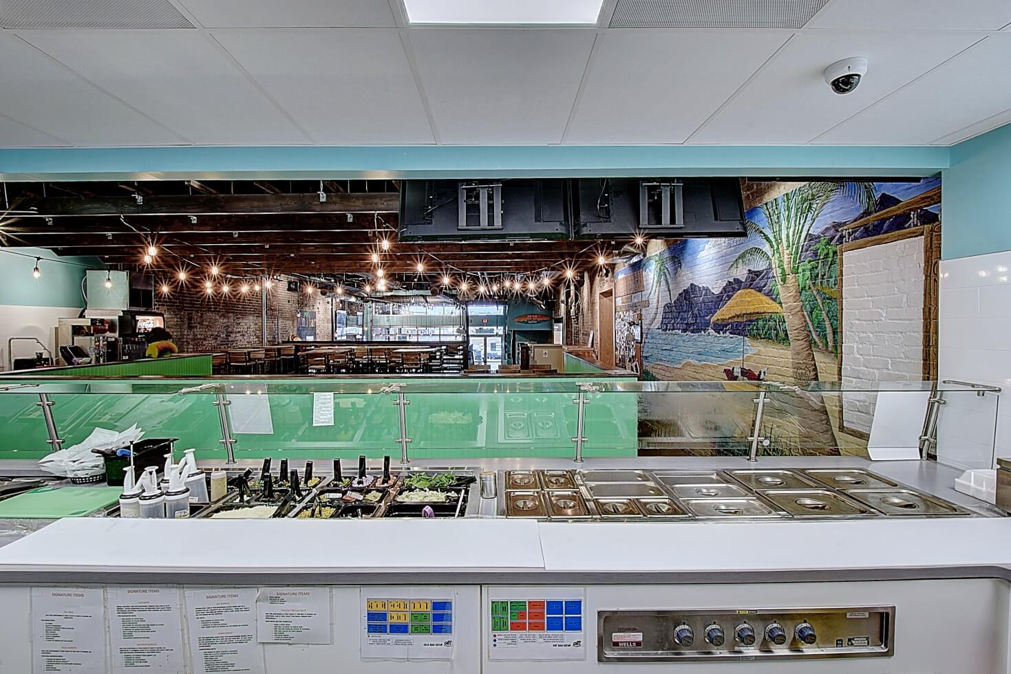 A modern kitchen with a bright interior, featuring counters, food displays, and decorative lighting.