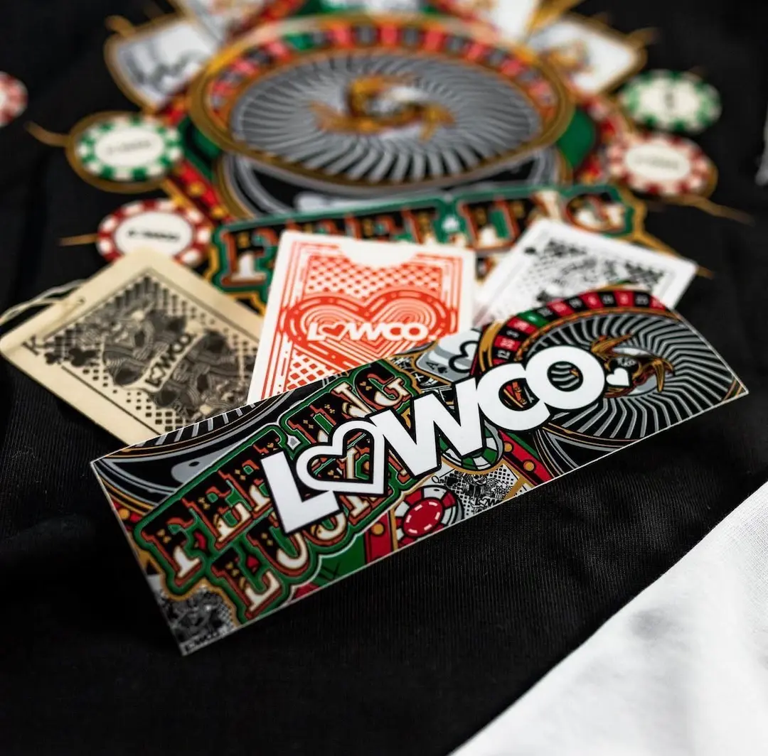 Close-up of Lowco Automotive Feeling Lucky sticker and casino-themed graphic details printed on apparel fabric.