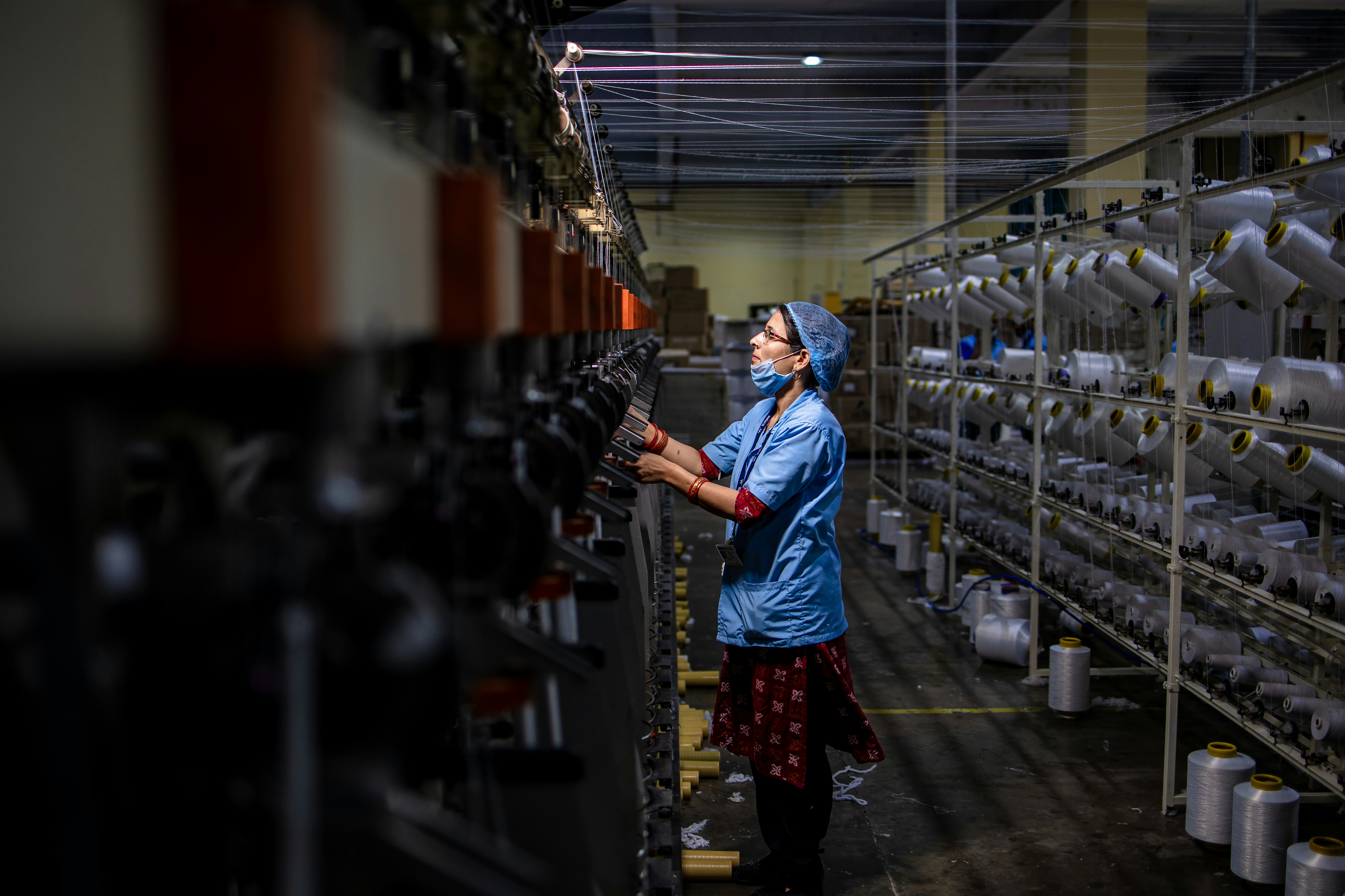 Factory worker tending to machinery and threads.