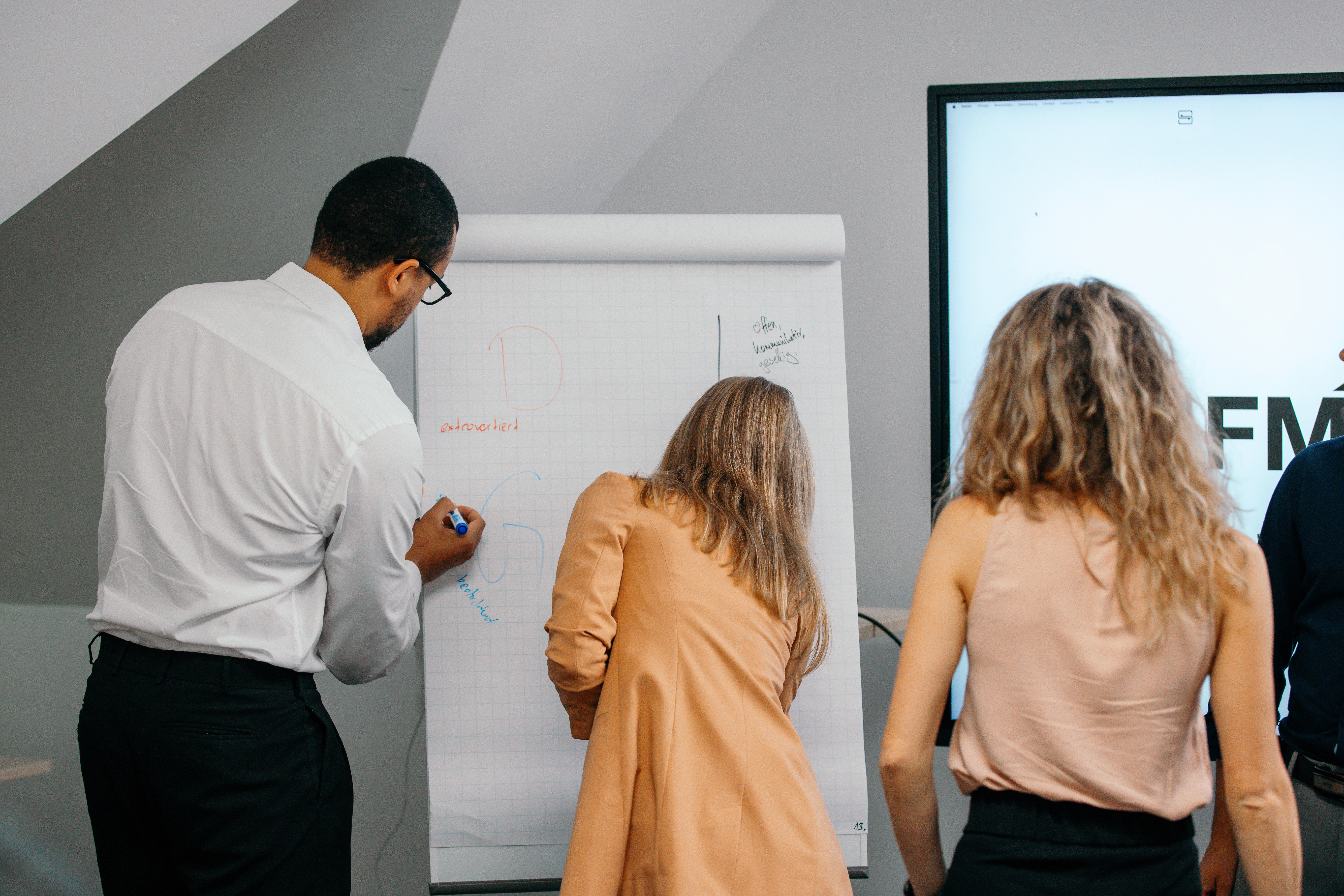 a group of people sitting around a table with laptops