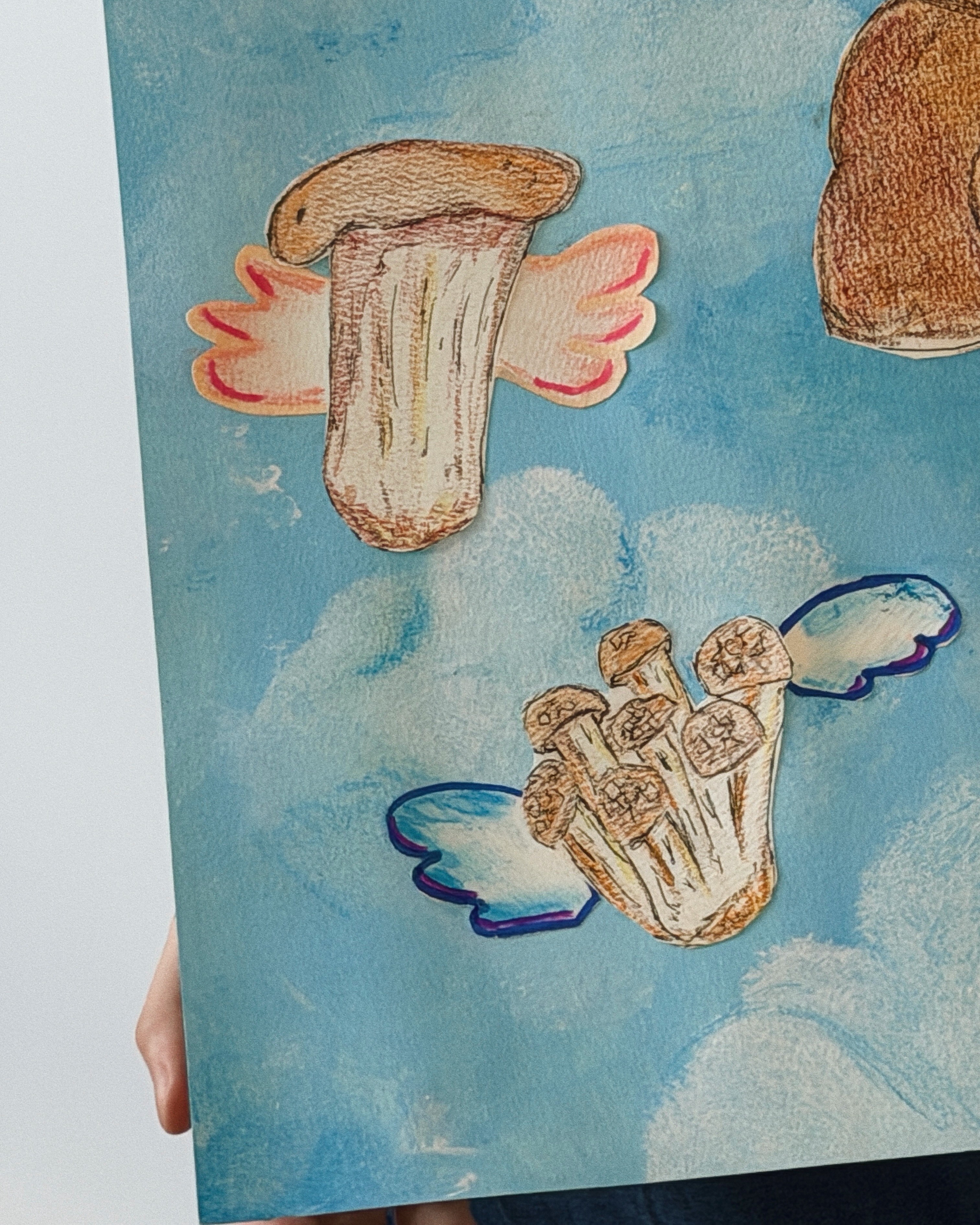 A child carefully painting detailed mushroom illustrations on white paper next to a tray of real mushrooms during a Noljak Basic Creative class at Rookids BGC.