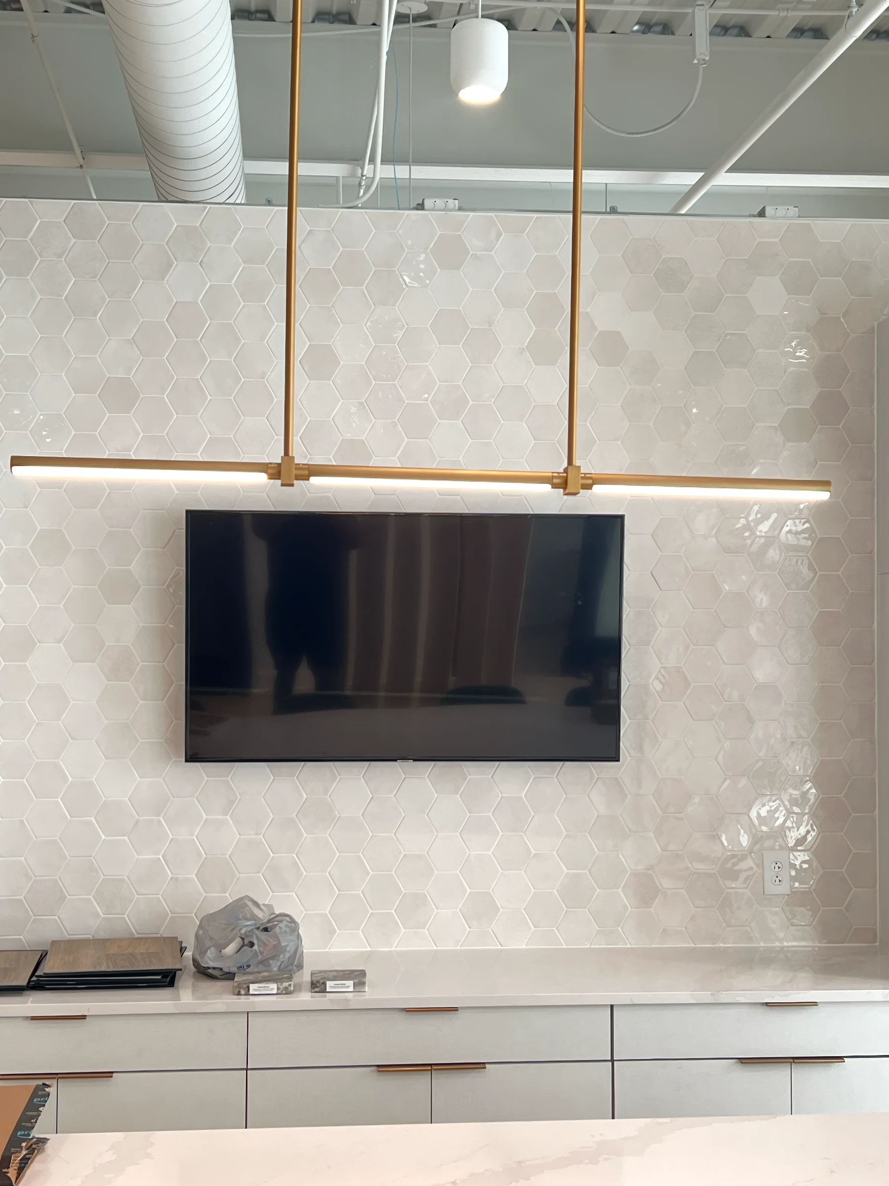A wall-mounted screen above cabinetry against a tiled wall in a shared interior.