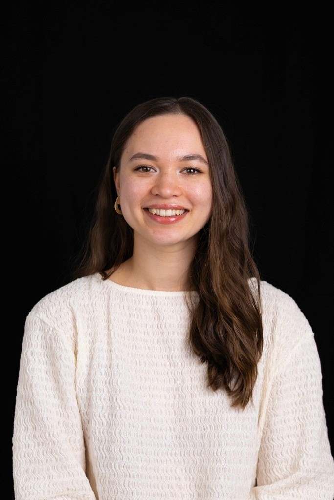 Portrait of a person in a pink sweater against a light background