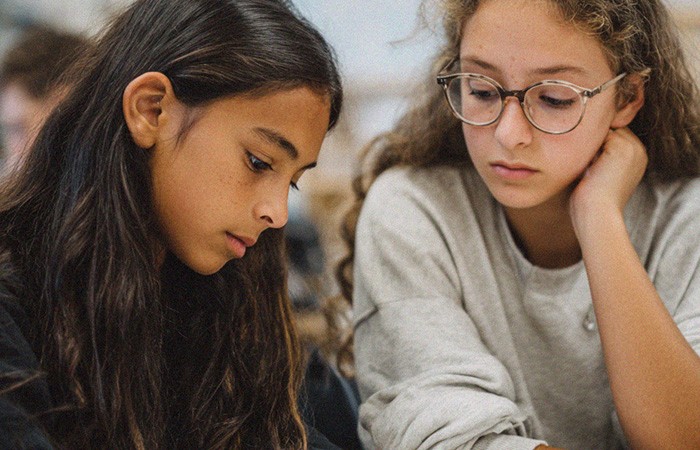 Two students focused on reading and working together on an assignment.