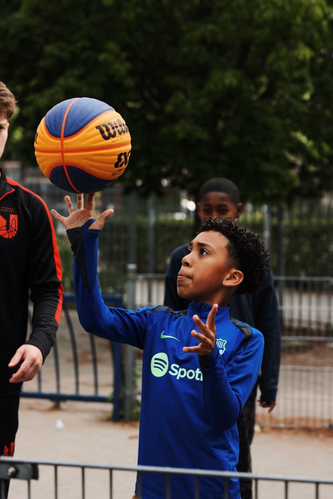 A muscular man smiling while performing a hanging leg raise on gymnastic rings in a bright fitness studio.