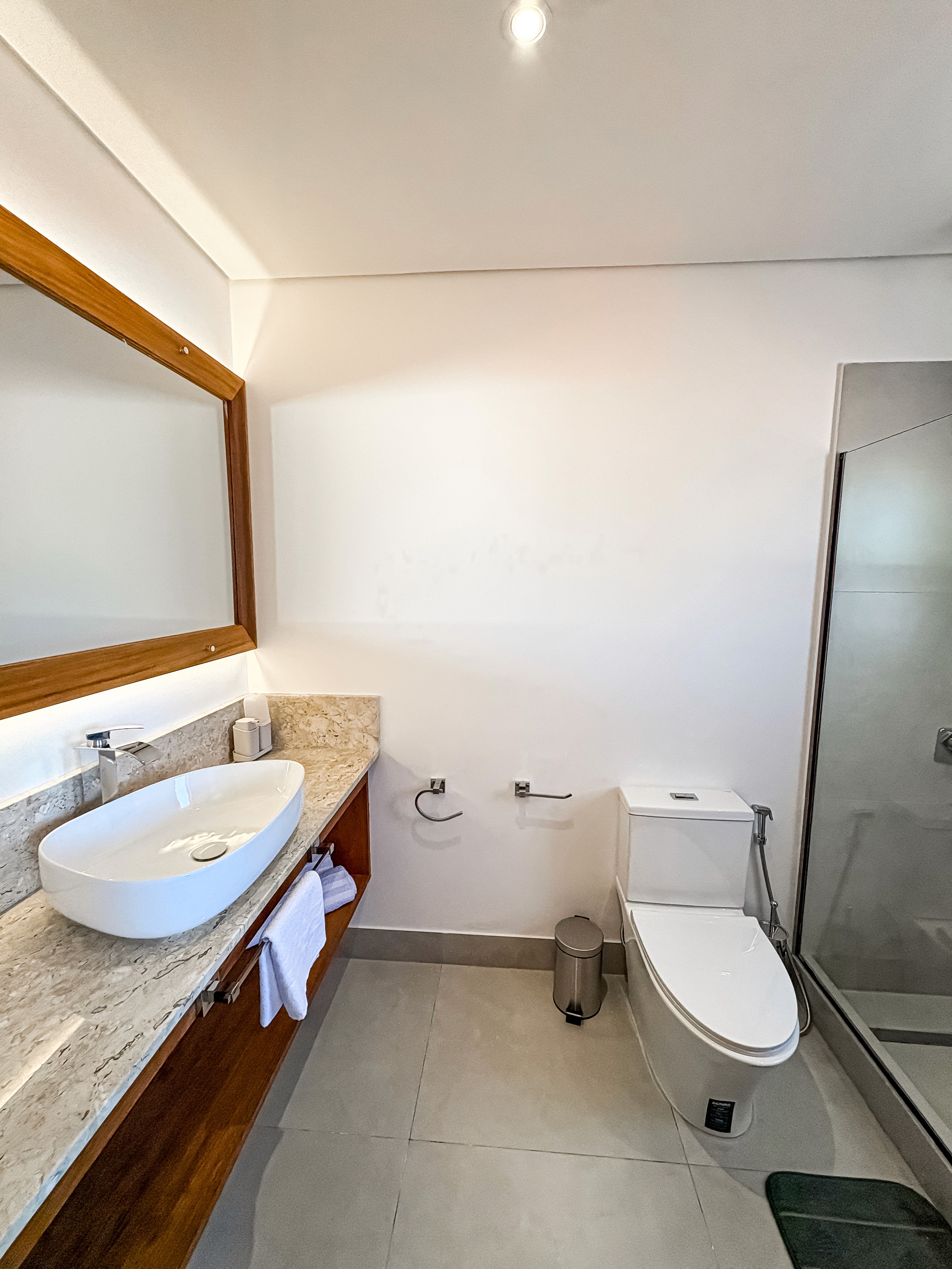 a soft linen lounge chair, driftwood side table, pampas grass in ceramic vase, with the beach faintly visible through floor-to-ceiling windows