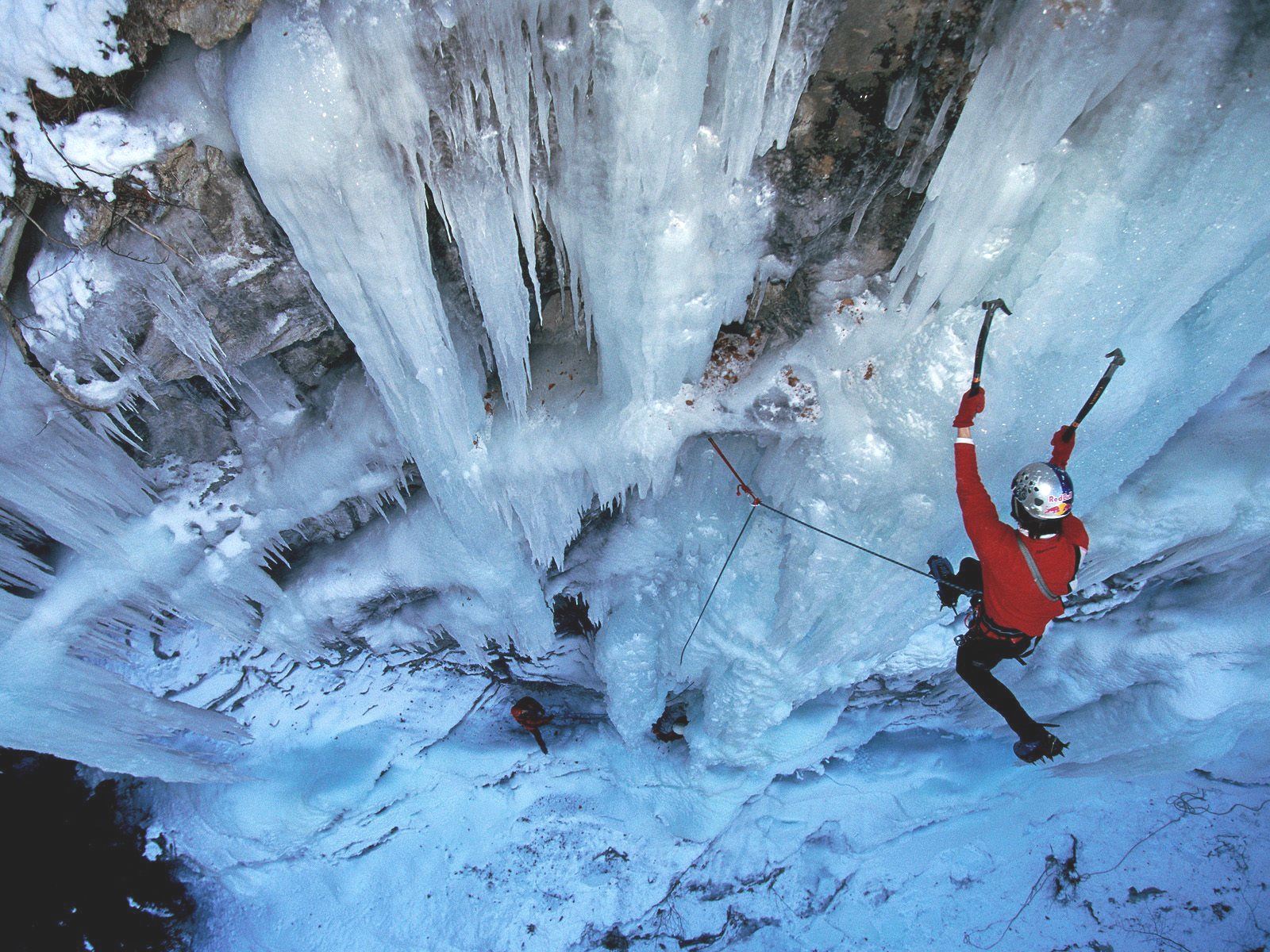Ice climber practicing ice tool placement and movement on vertical ice during an ice climbing fundamentals clinic course in the Dolomites.