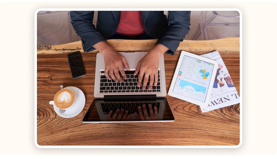  Person working on laptop with analytics dashboard, coffee, phone, and tablet&nbsp;