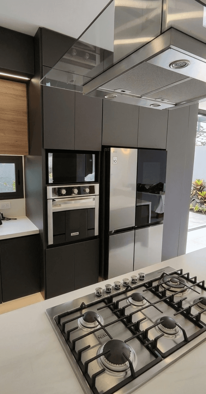 A serene outdoor seating area with two chairs, surrounded by lush greenery and a glassed-in structure.