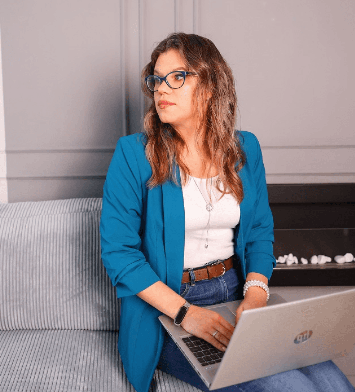 Professional web designer working on a laptop, styled in a modern neutral workspace, representing conversion-focused Shopify website design for product-based businesses.